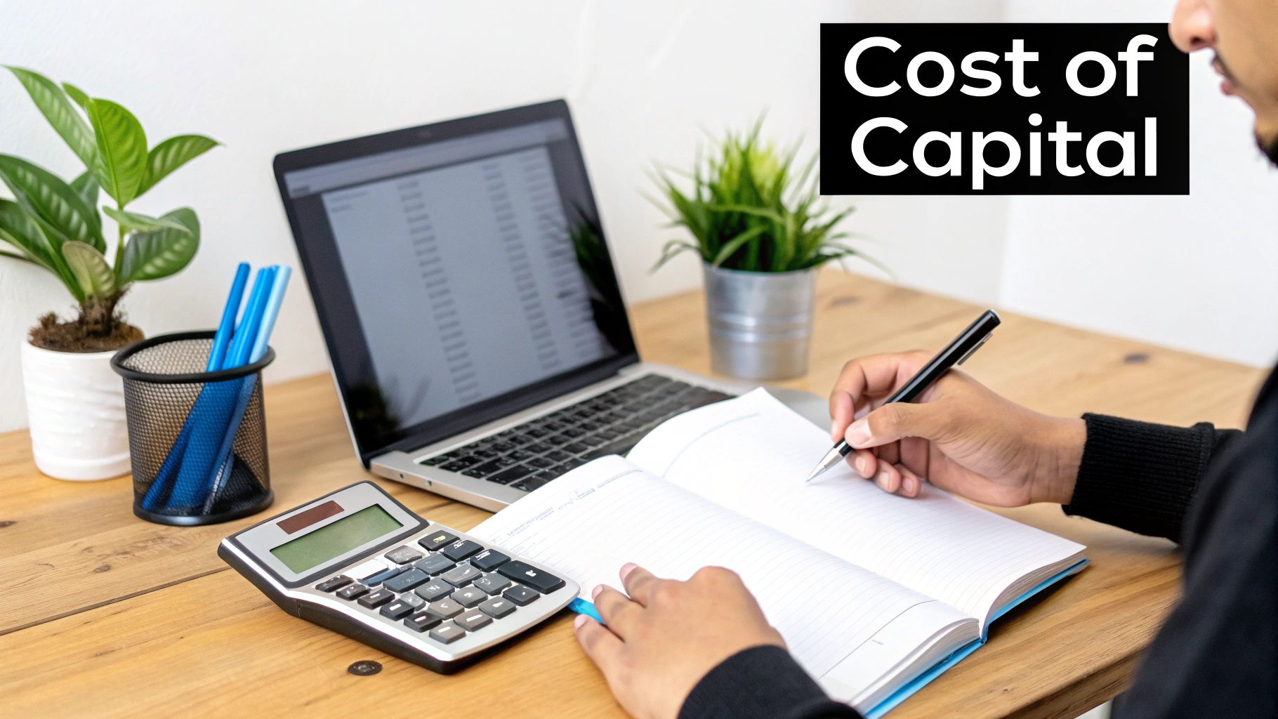 A person calculates the cost of capital on a wooden desk with a laptop, calculator, and notebook.