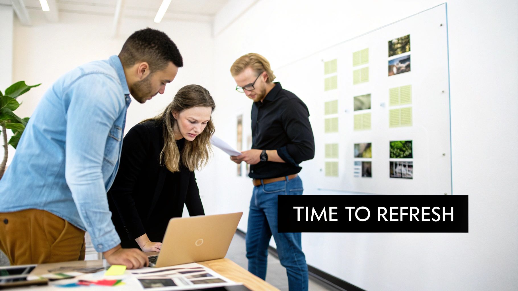 Three marketing professionals collaborating on brand refresh strategy with laptop and creative materials in modern office