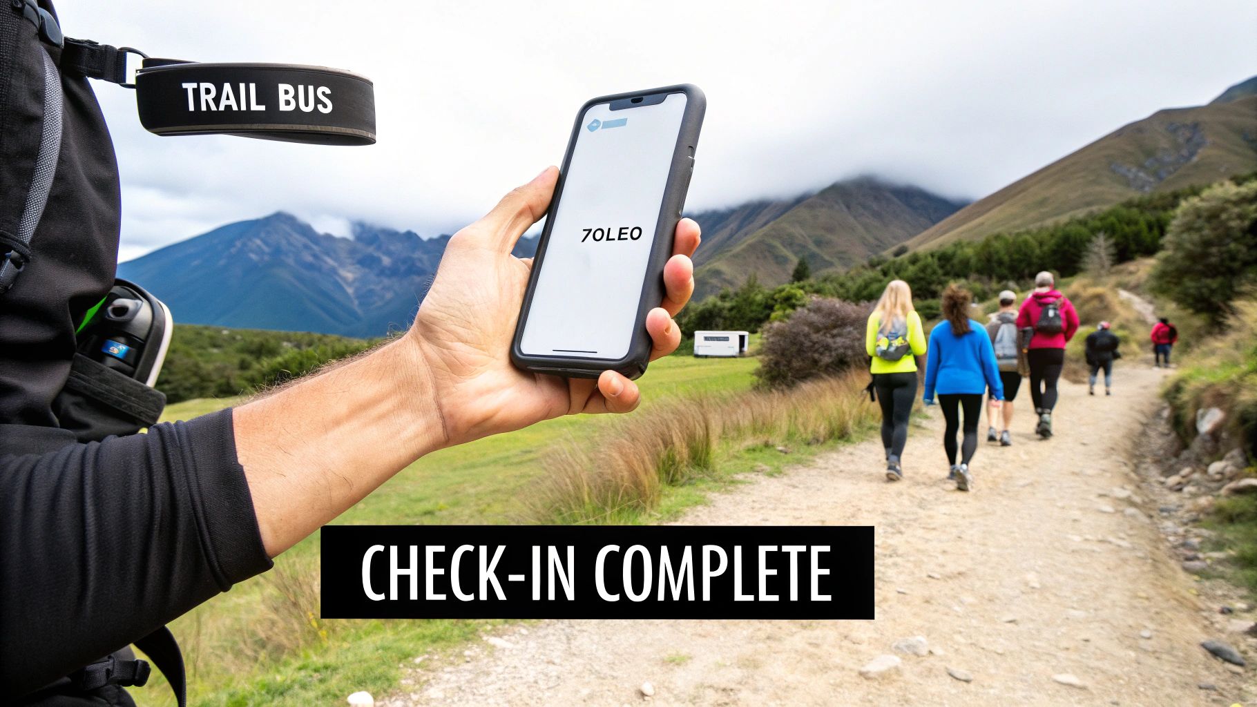 A hiker holds a ZOLEO satellite communicator displaying 'CHECK-IN COMPLETE' on a mountain trail.