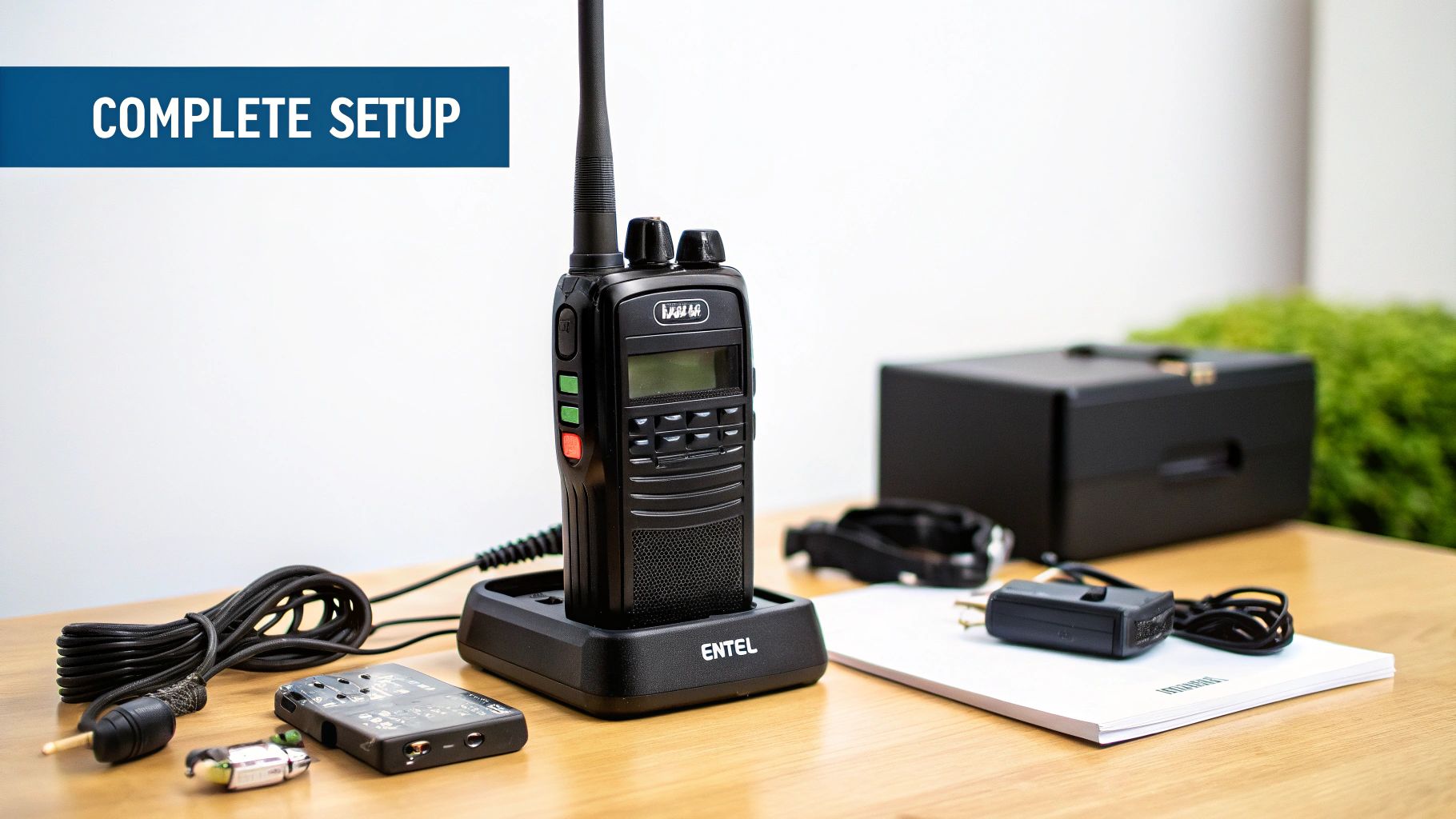 A close-up of the Entel DX422 radio showing its rugged build and clear display, placed on a surface with various professional accessories like a remote speaker microphone and a multi-bay charger.