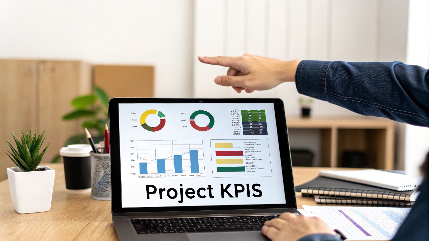 A person's hand points at a laptop screen displaying project KPIs, charts, and business data.