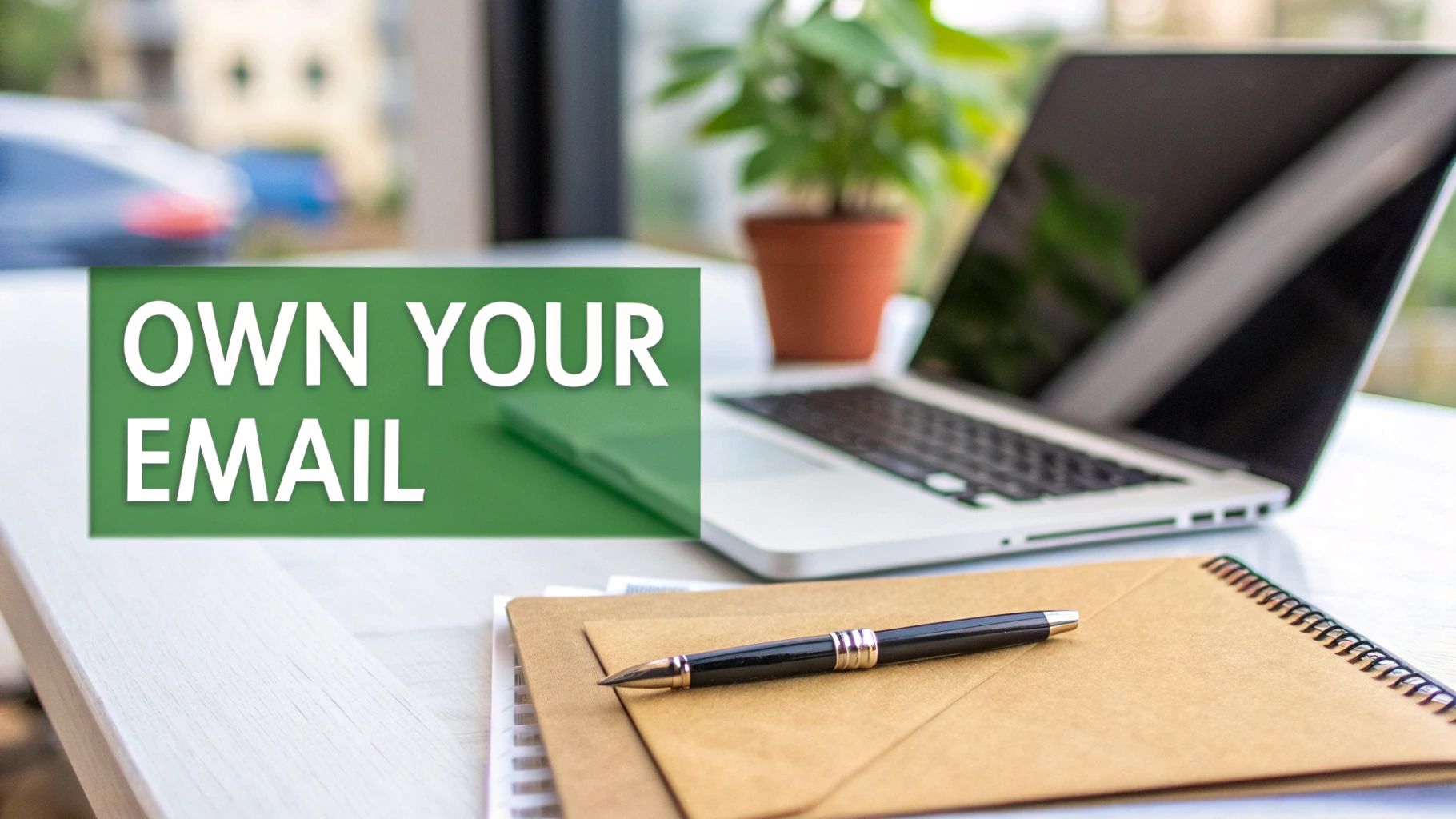 A desk setup with a laptop, plant, and 'OWN YOUR EMAIL' text, emphasizing digital control.