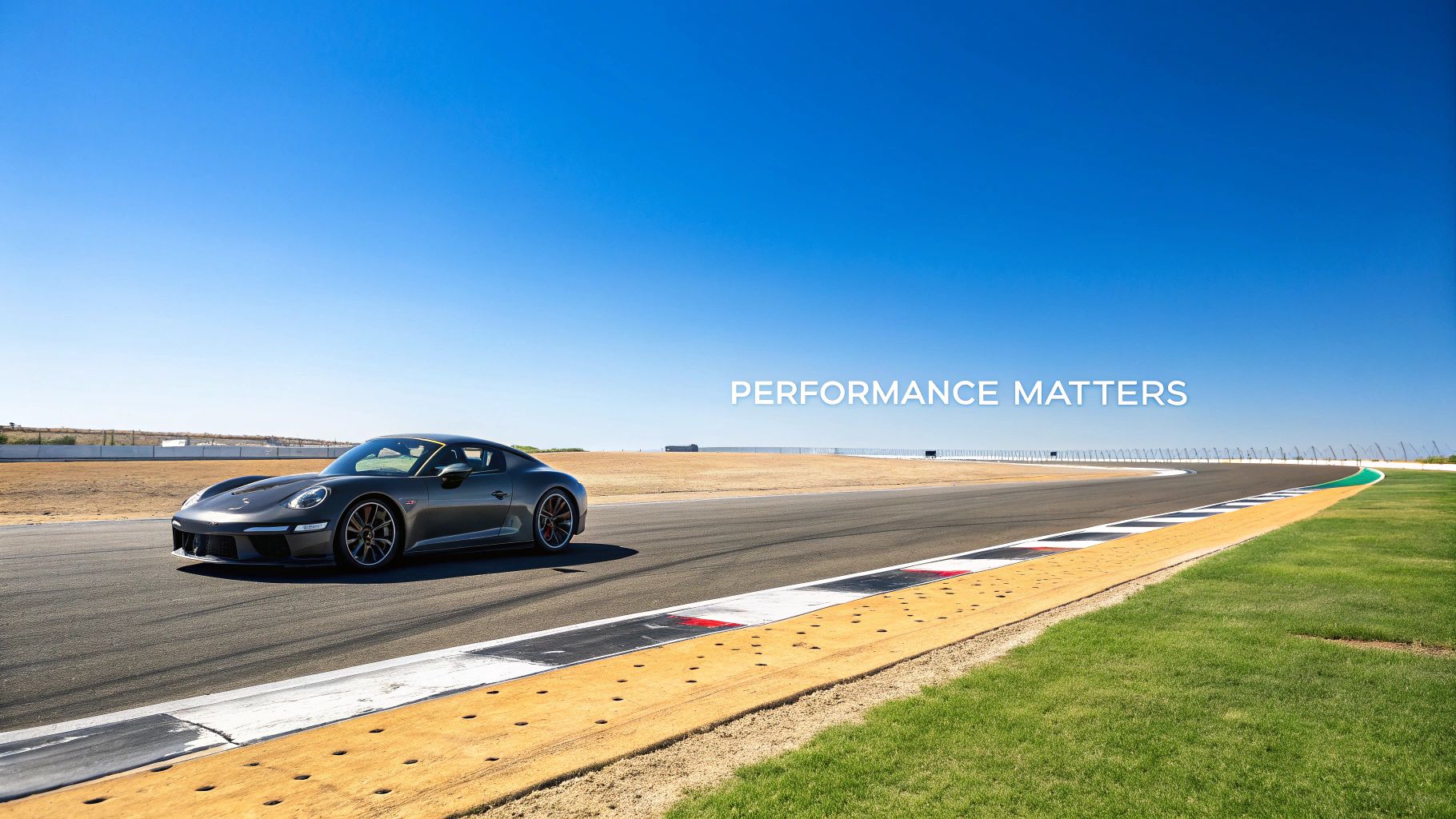 A sleek grey Porsche sports car on a race track with "PERFORMANCE MATTERS" text against a clear blue sky.