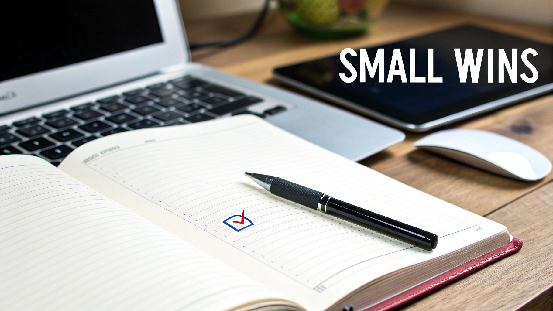Desk with laptop, tablet, open notebook showing a checkmark, pen, and 'SMALL WINS' text.