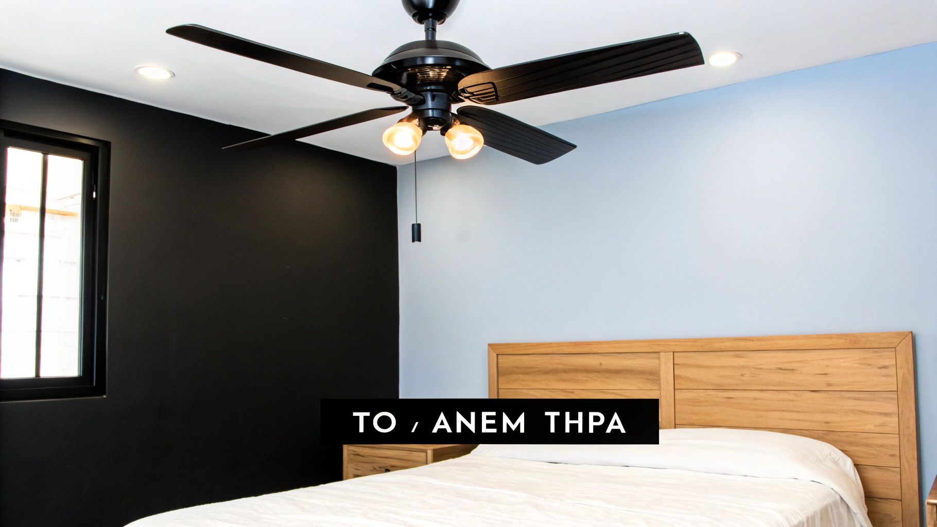 Ένα μοντέρνο υπνοδωμάτιο με μαύρο ανεμιστήρα οροφής, ξύλινο κεφαλάρι κρεβατιού και διχρωμία στους τοίχους.