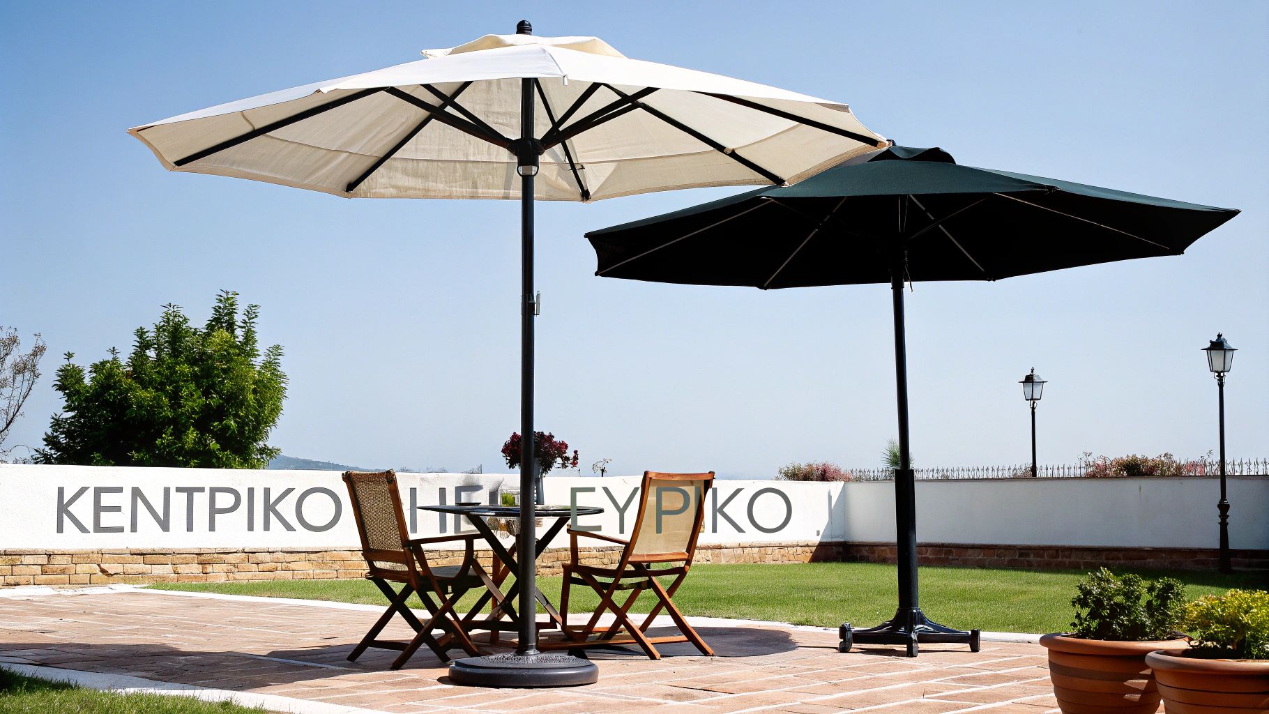 Δύο ομπρέλες κήπου, μία μπεζ και μία σκούρα, προστατεύουν ένα τραπέζι με καρέκλες σε εξωτερικό χώρο με γκαζόν.