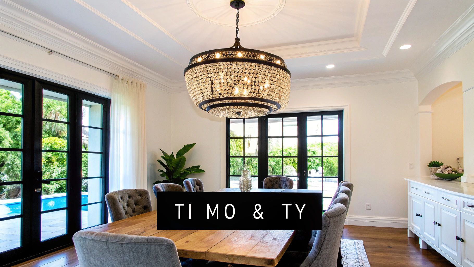 Φωτεινή τραπεζαρία με εντυπωσιακό κρυστάλλινο πολυέλαιο, ξύλινο τραπέζι και γαλλικές πόρτες με θέα σε πισίνα.