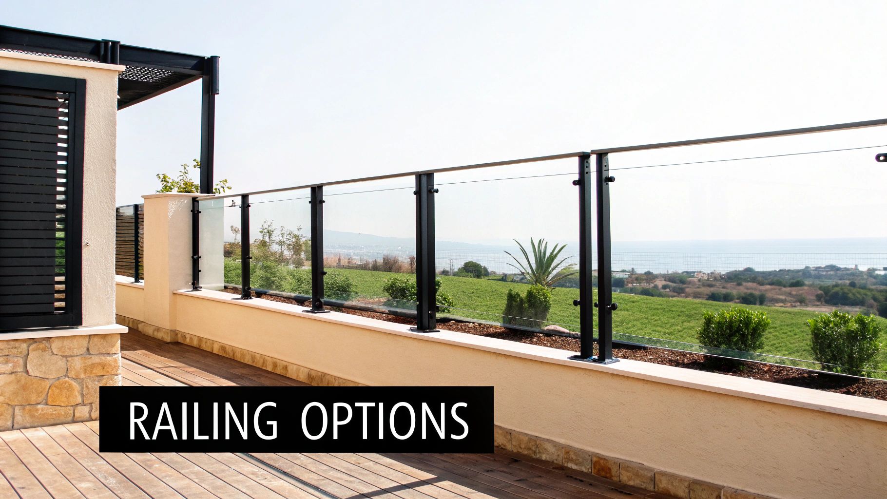 A modern balcony features a glass railing with black posts, offering a clear view of the green landscape and ocean.