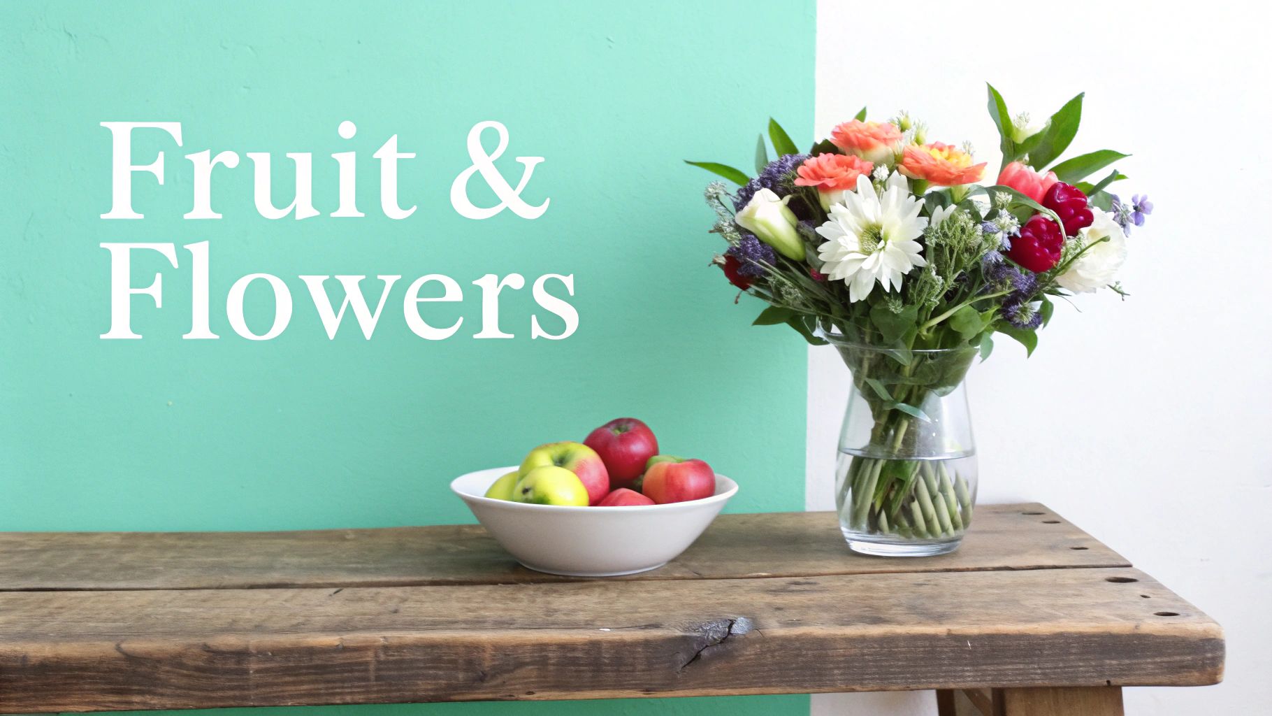 A wooden table with a bowl of fresh apples and a vase of colorful flowers under a "Fruit & Flowers" sign.