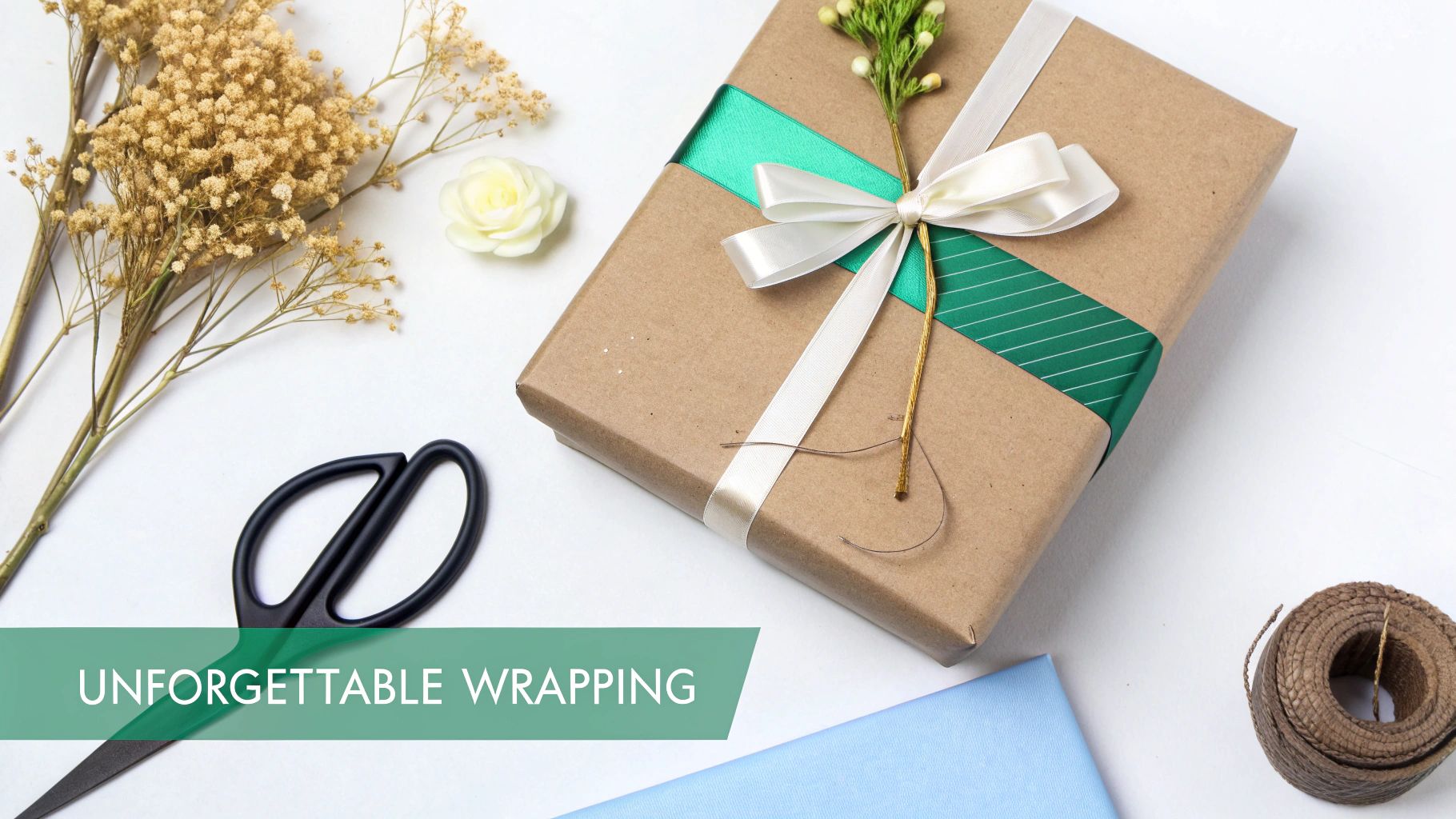 A person wrapping a Christmas gift with brown paper, twine, and a sprig of festive foliage.