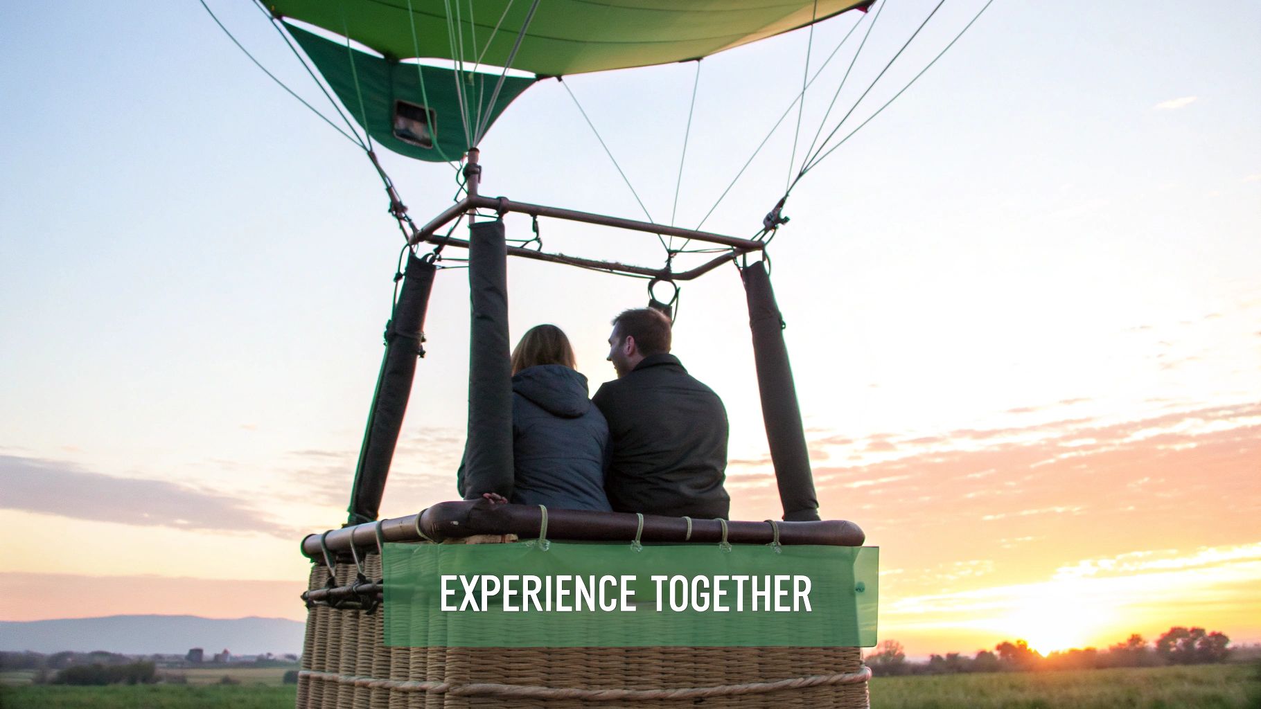 Rear view of a couple enjoying a scenic hot air balloon ride at sunset, with text "EXPERIENCE TOGETHER".