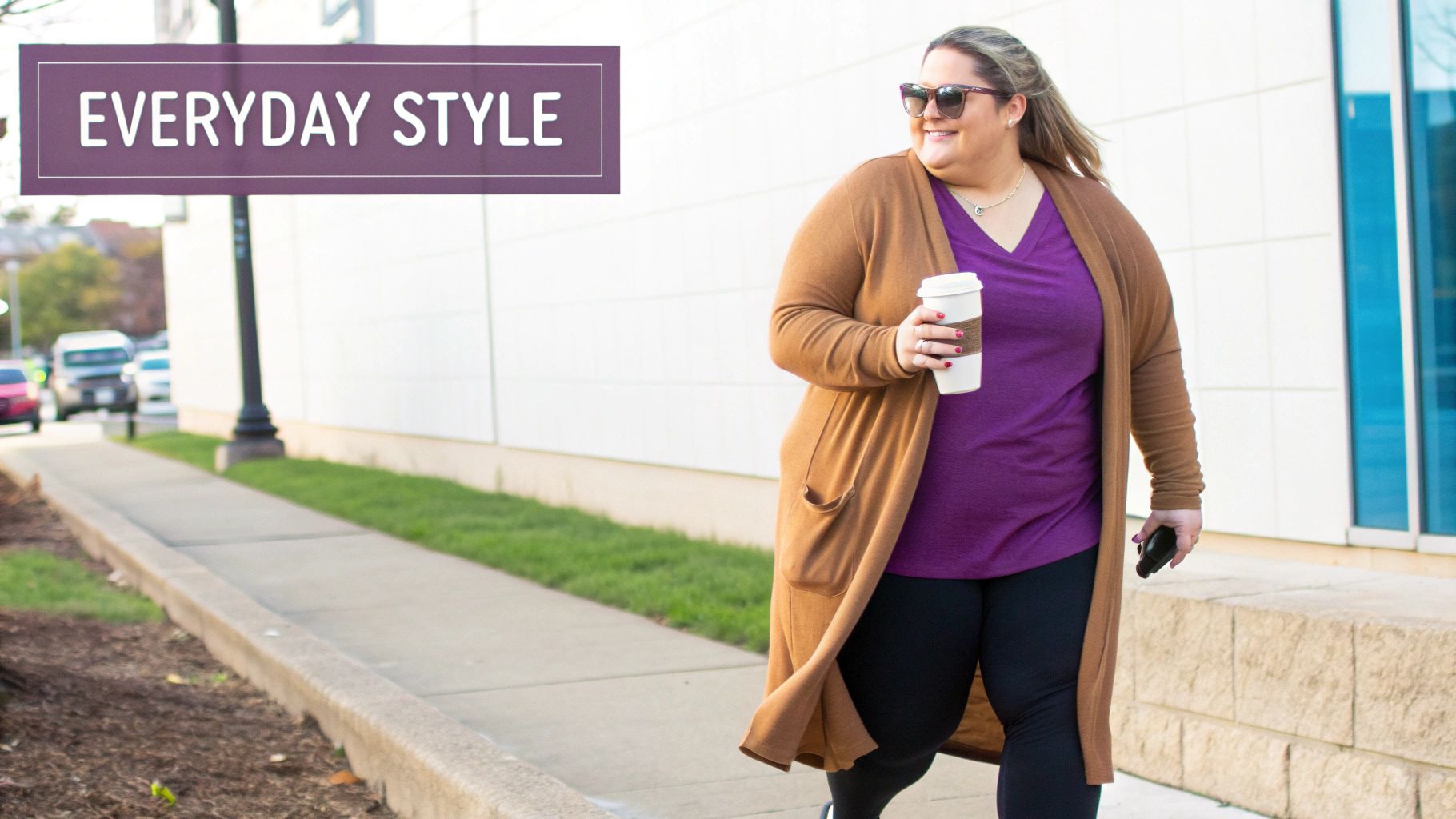 A plus size woman smiling and looking confident in her activewear on a city street.