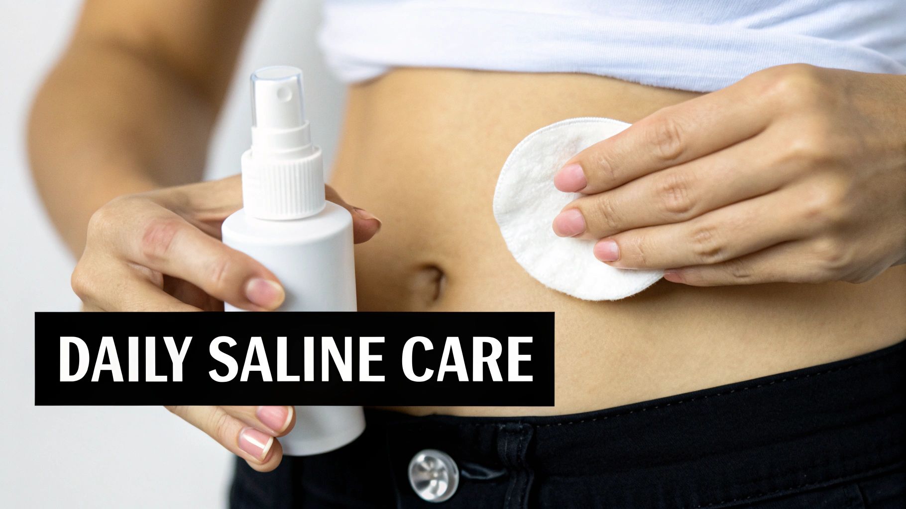A person's hands performing daily saline care on a belly button piercing with a spray and cotton pad.