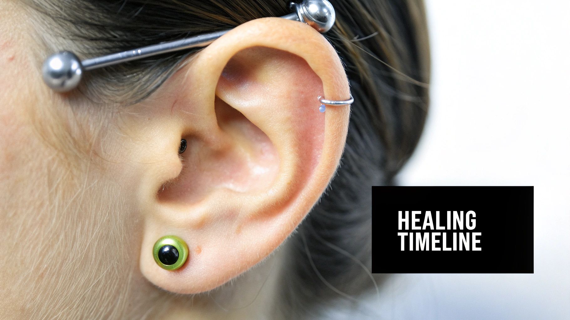 A person showing their industrial piercing with a simple silver barbell.