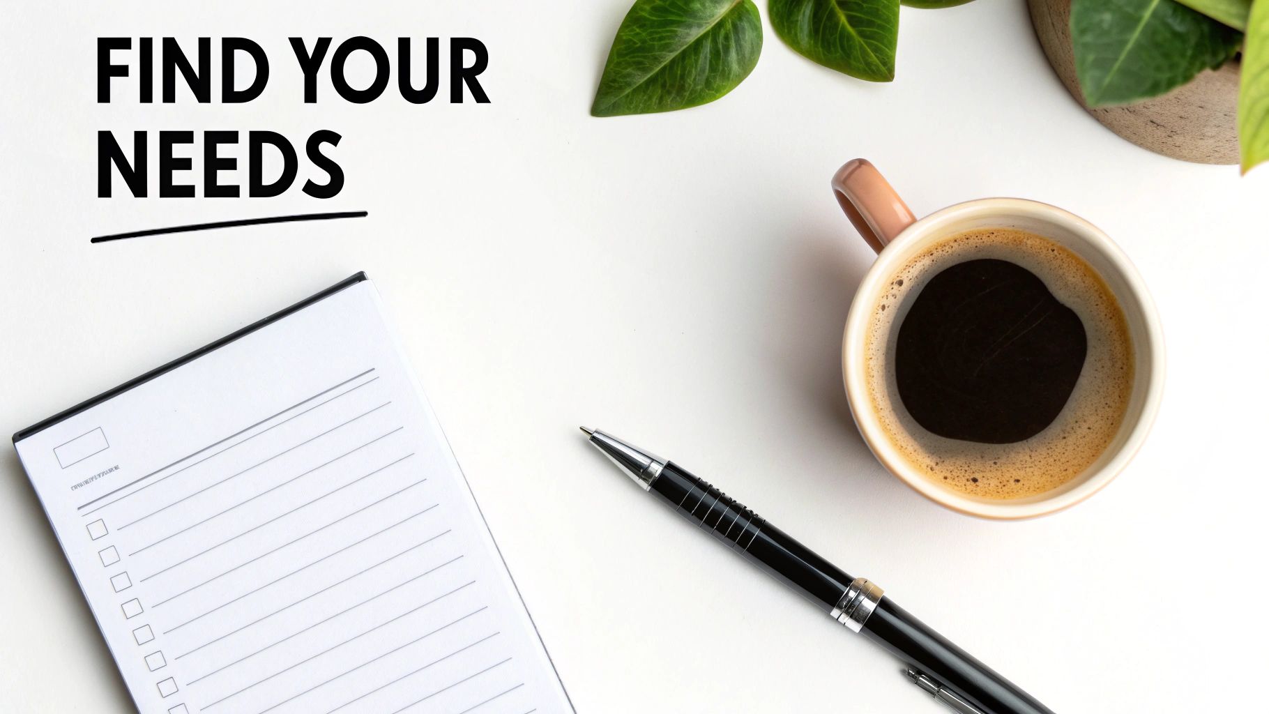 Overhead view of a white desk with 'FIND YOUR NEEDS' text, a notebook, pen, coffee, and plant.