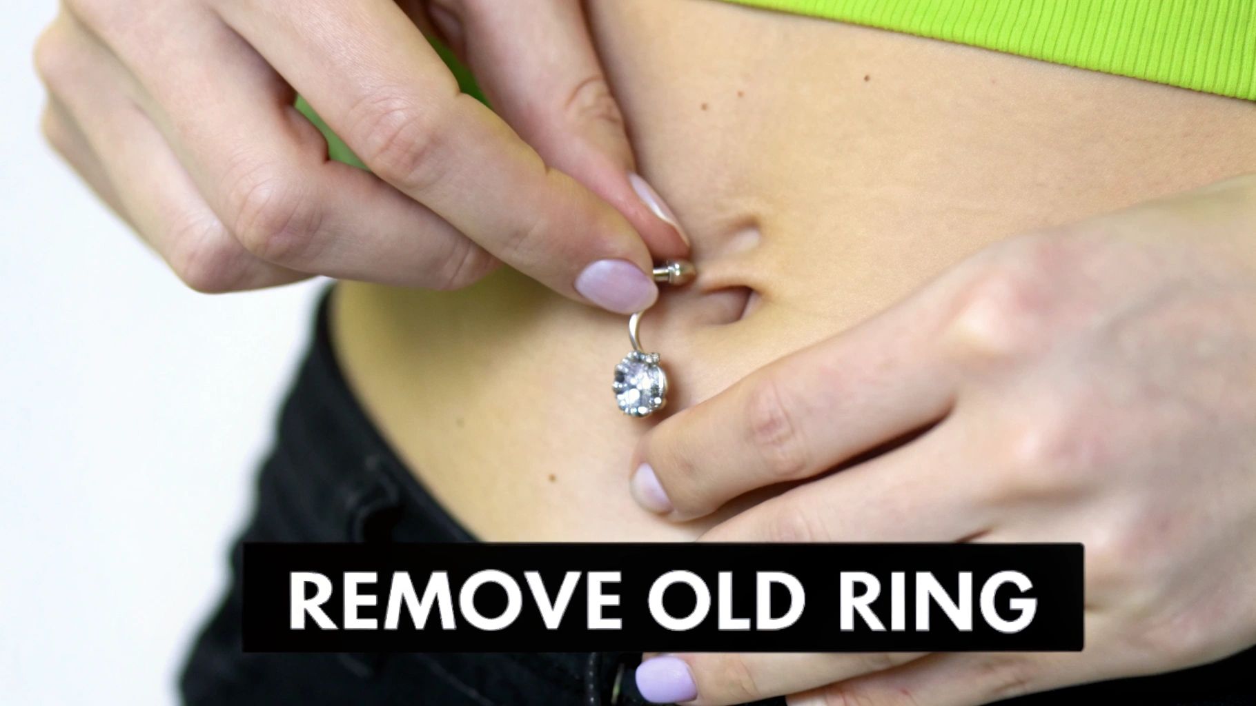 A person holding a new, clean belly button ring, ready to insert it.