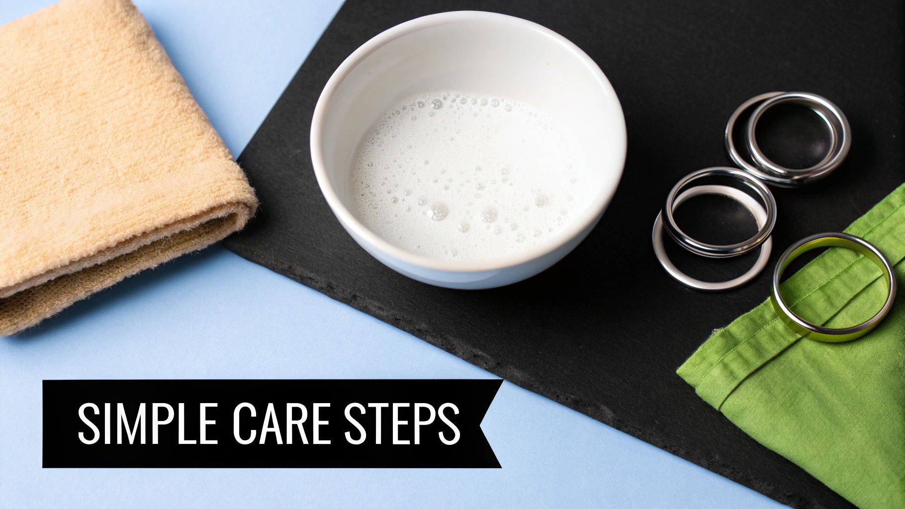 Flat lay of cleaning items including a bowl of soapy water, towel, and metal rings for simple care.