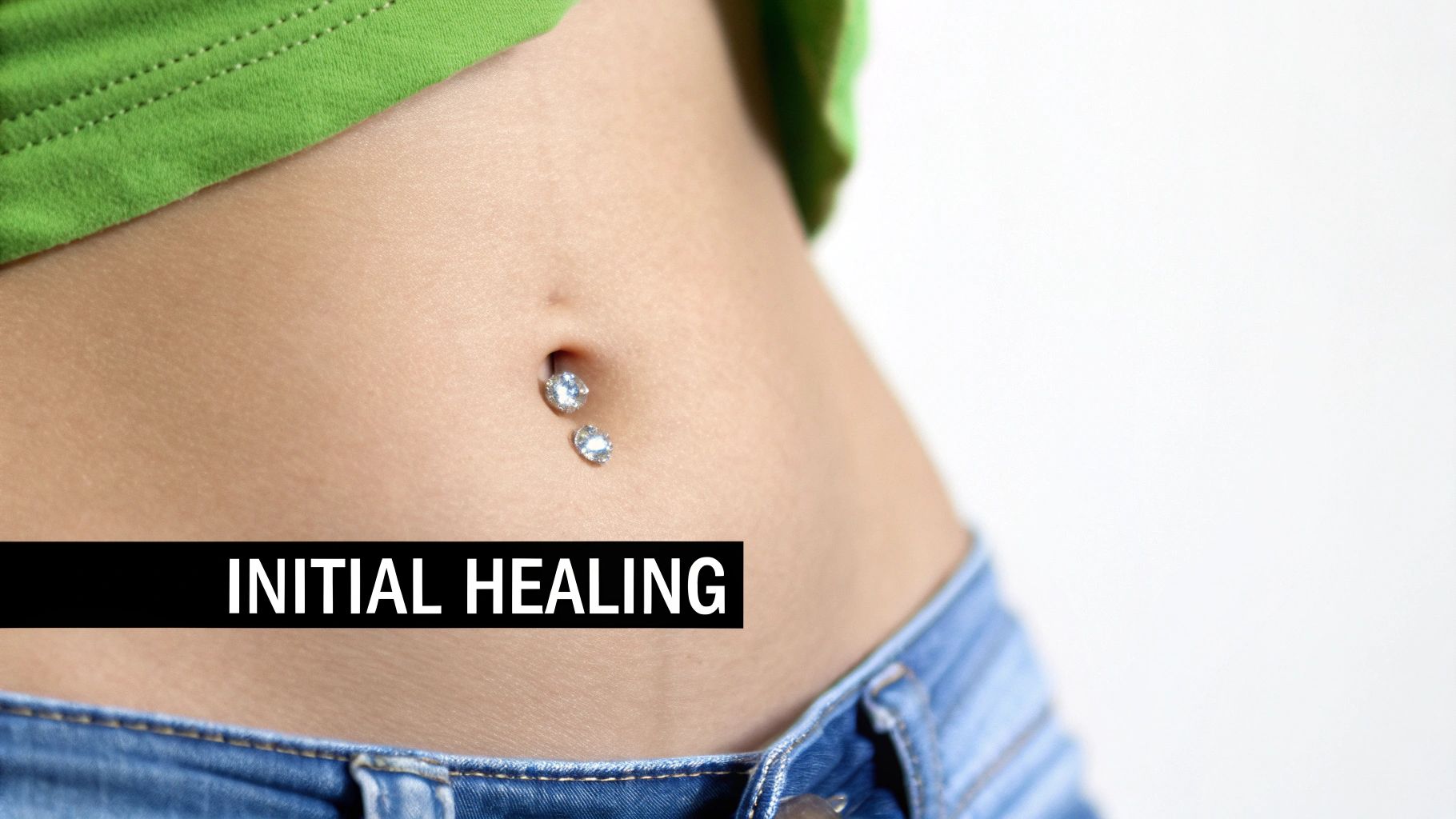 A person showing their newly pierced navel with simple, elegant jewelry.