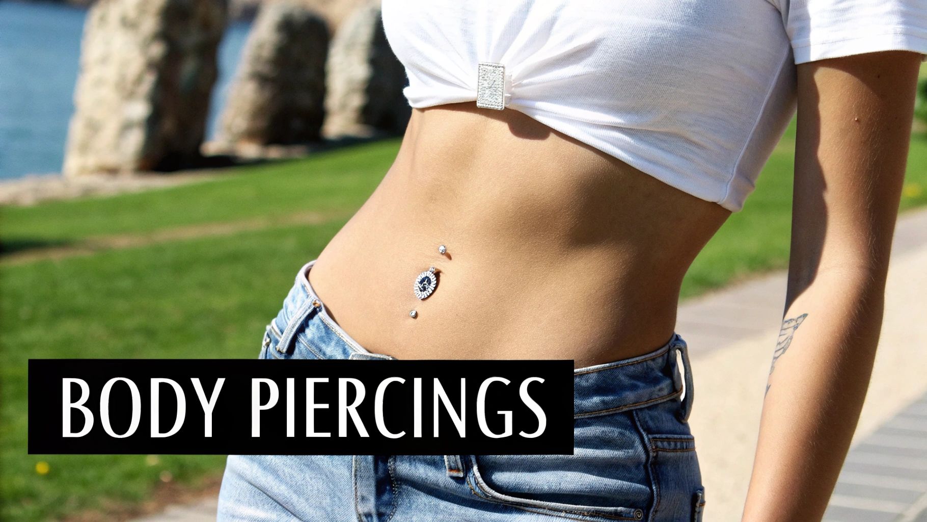 Close-up of a woman's belly button with ornate navel and dermal piercings, wearing denim.