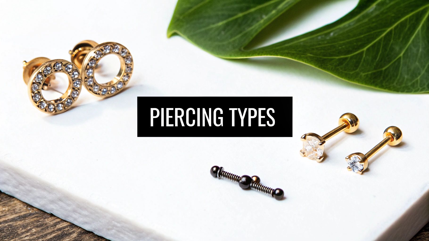 A selection of gold and black piercing jewelry, including studs and hoops, on a white surface.