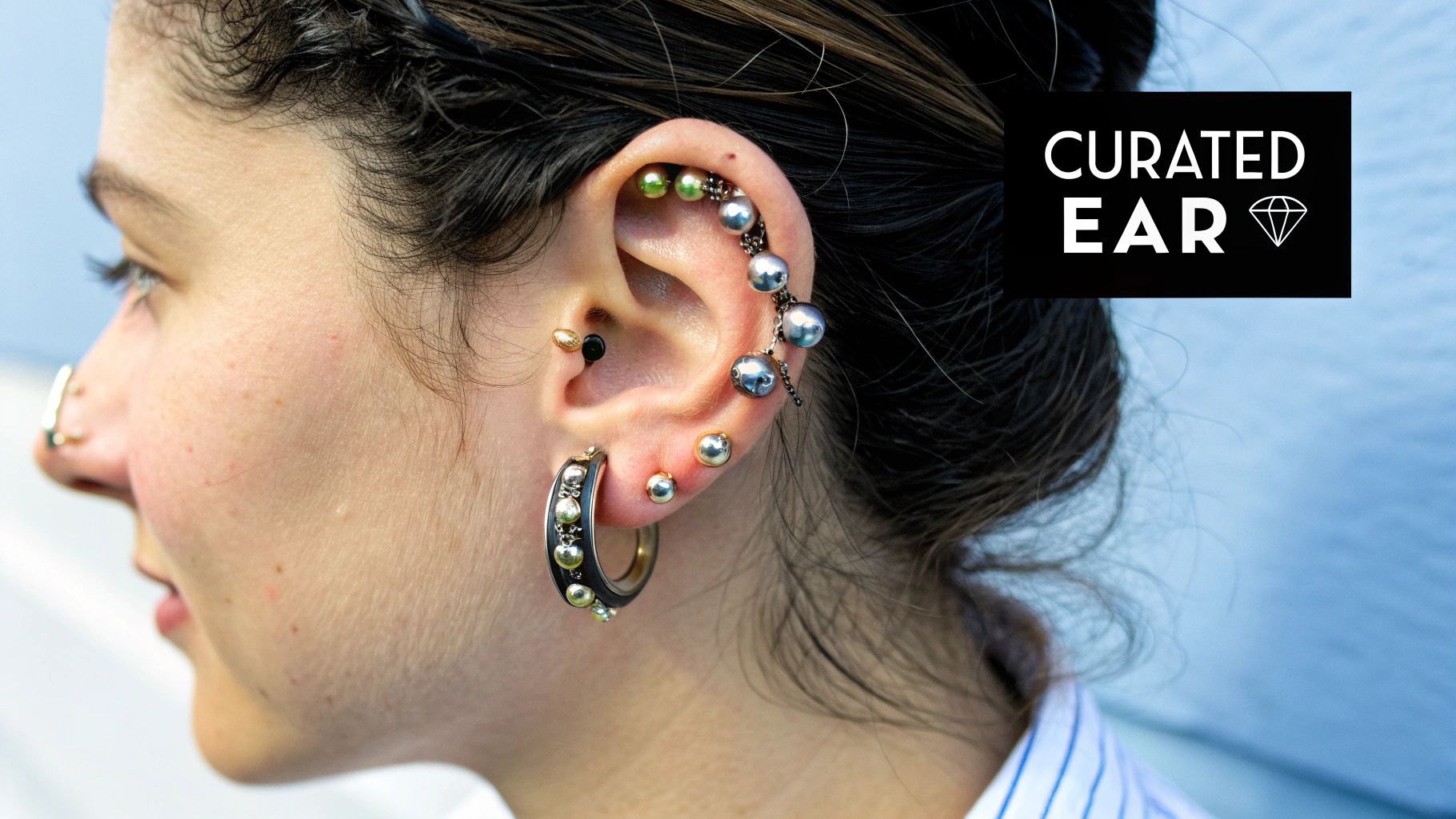 A person showing off a stylishly curated ear with multiple piercings.