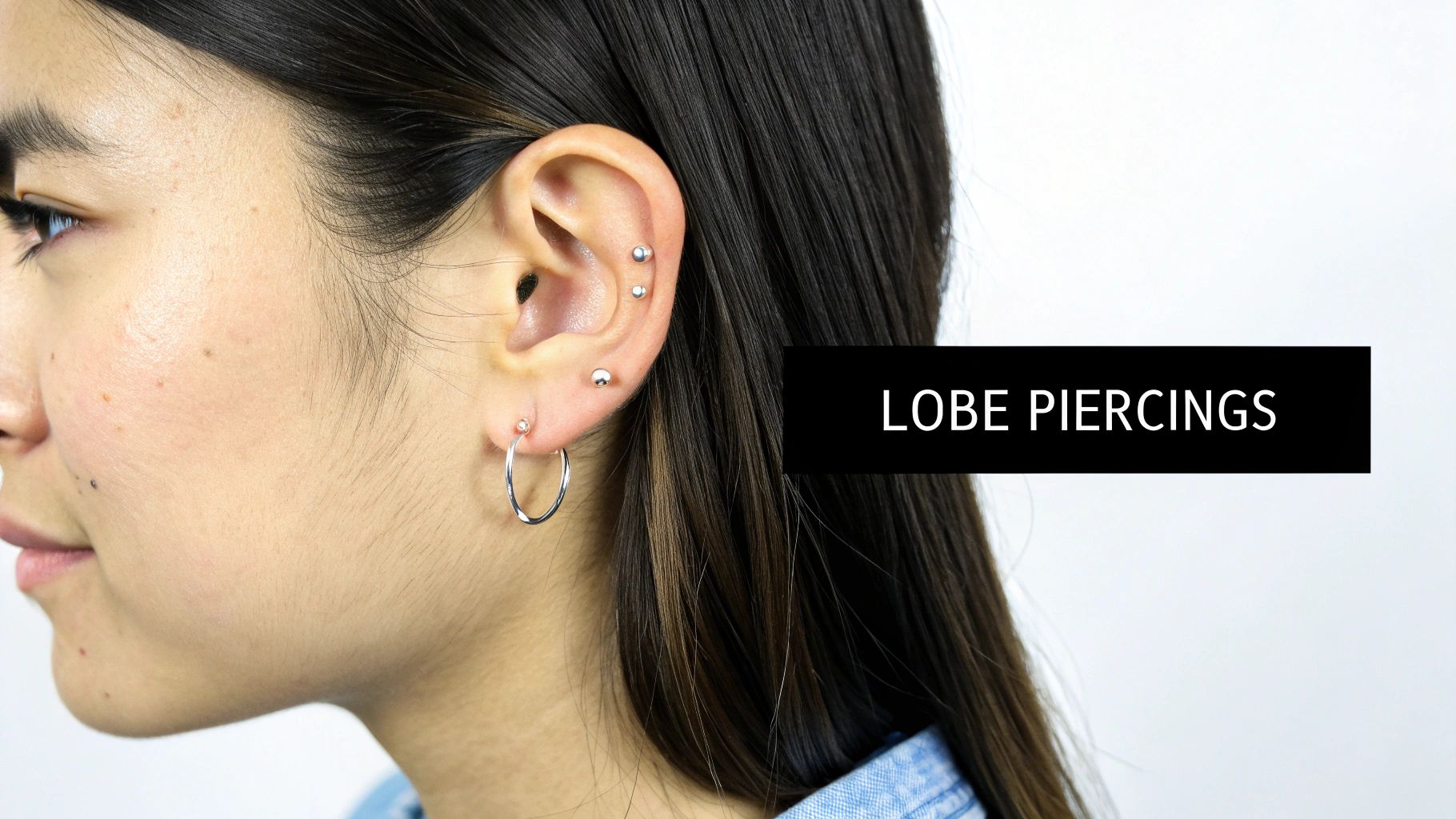 Close-up of a woman's ear with multiple silver piercings, including a hoop and studs.