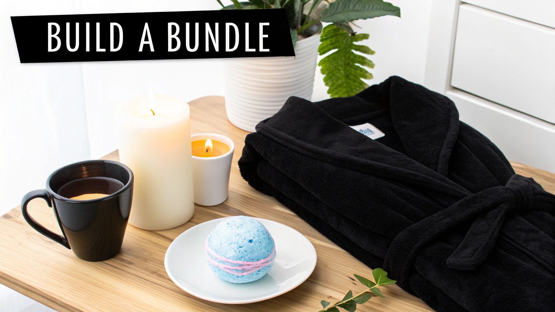 A black robe, blue bath bomb, two lit candles, and a mug on a wooden tray, perfect for a relaxing self-care bundle.