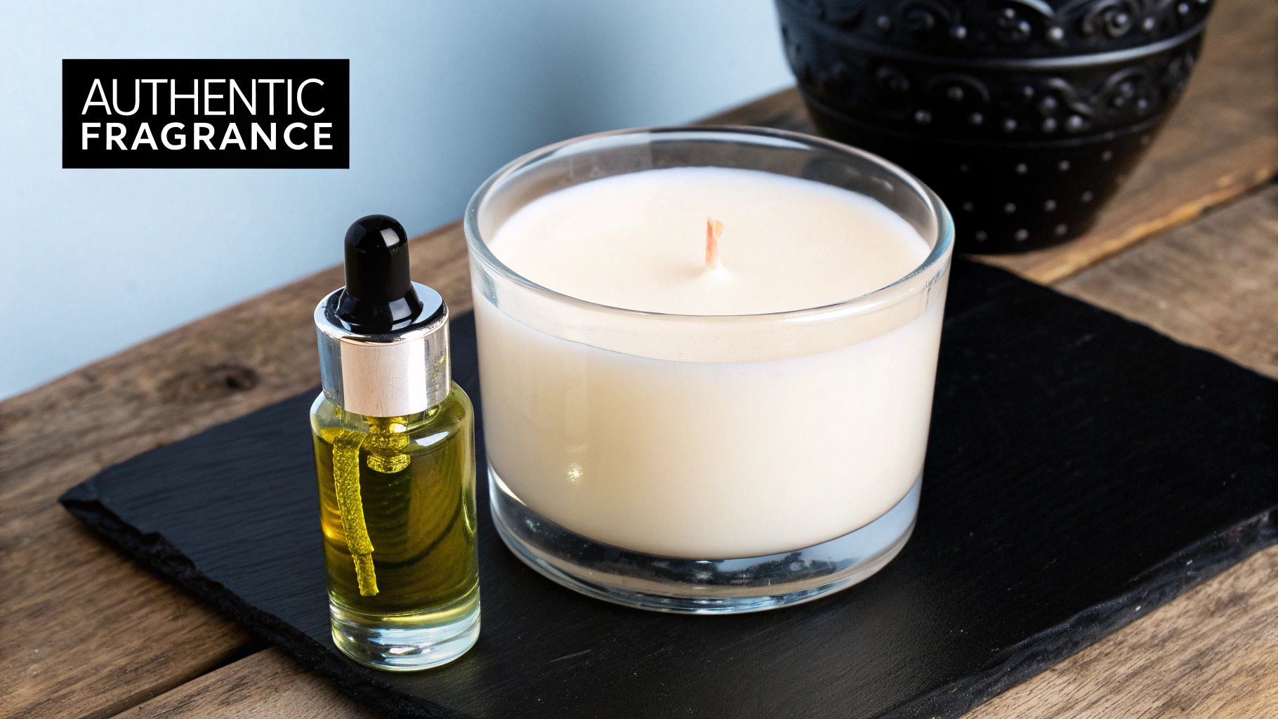 A glass candle and a dropper bottle with yellow liquid sit on a black slate, promoting authentic fragrance.