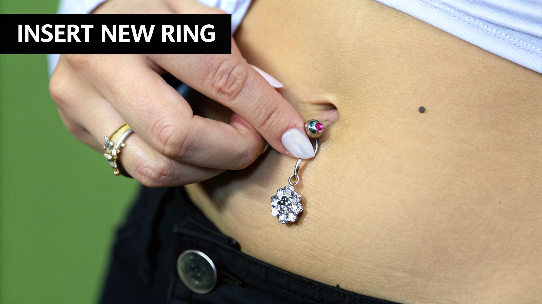 A close-up of a healed belly button piercing with a new, sparkling piece of jewelry in it.
