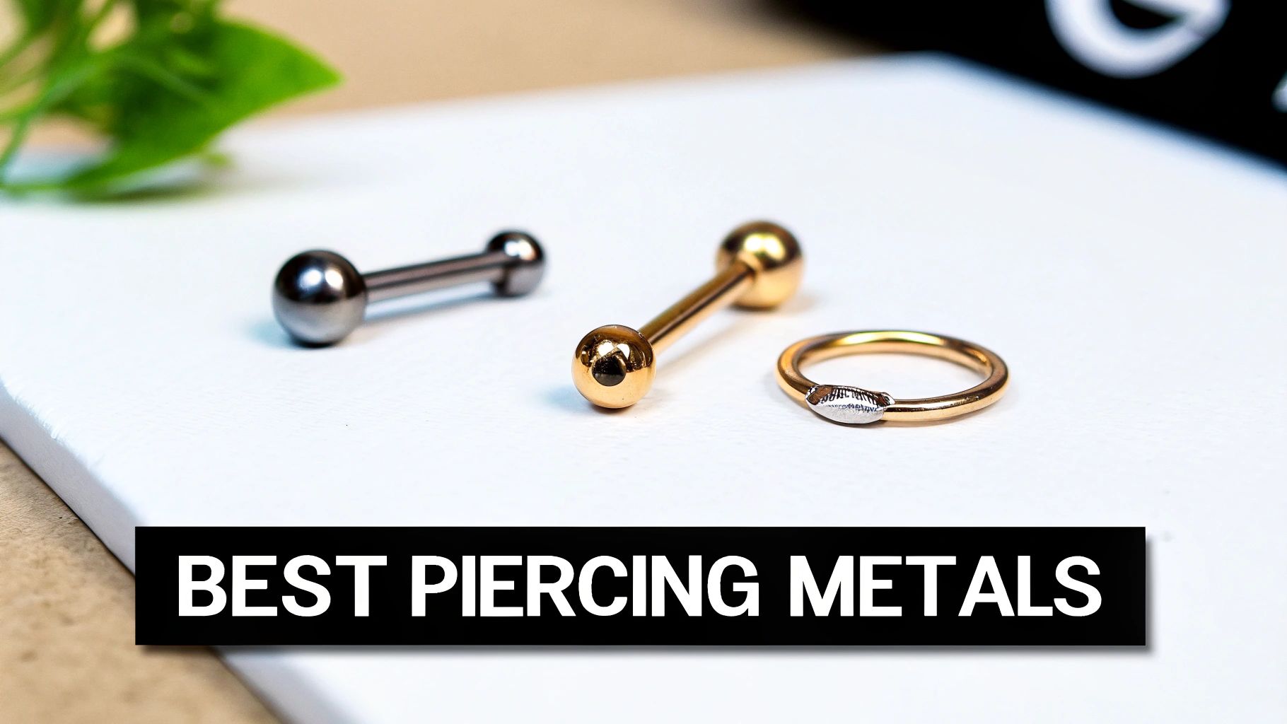 Close-up of different types of piercing jewelry: a silver barbell, a gold barbell, and a gold ring on a white surface.