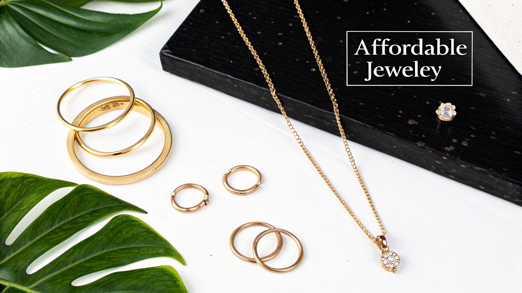 A flat lay of gold-colored affordable jewelry, including rings, a necklace, and a single earring.