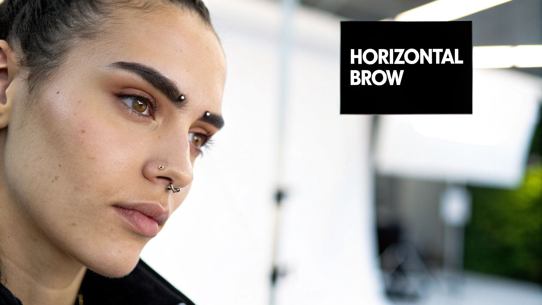 A person showing off a unique anti-eyebrow piercing.