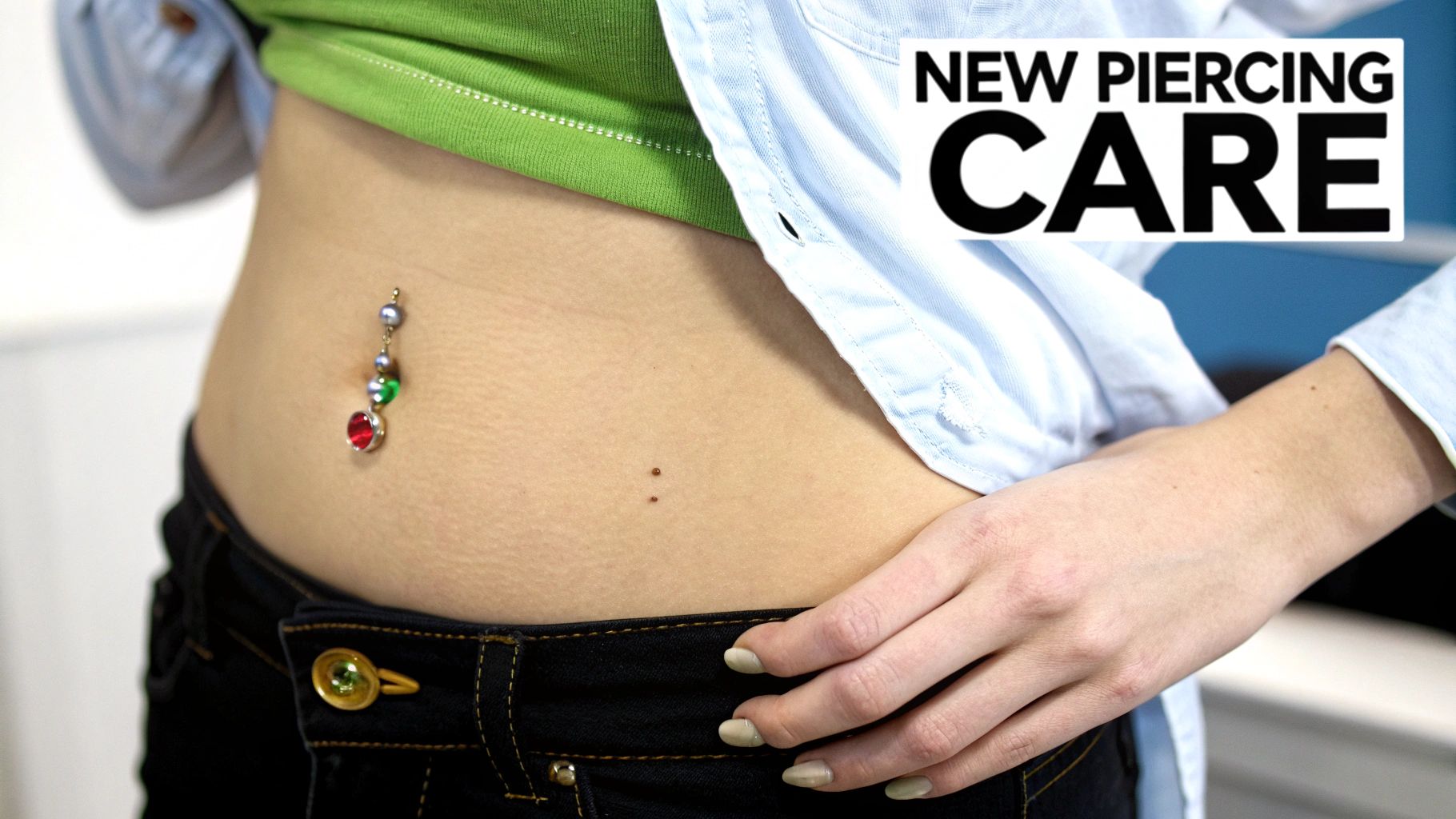 A person's belly button piercing with colorful dangling jewelry, illustrating new piercing care.