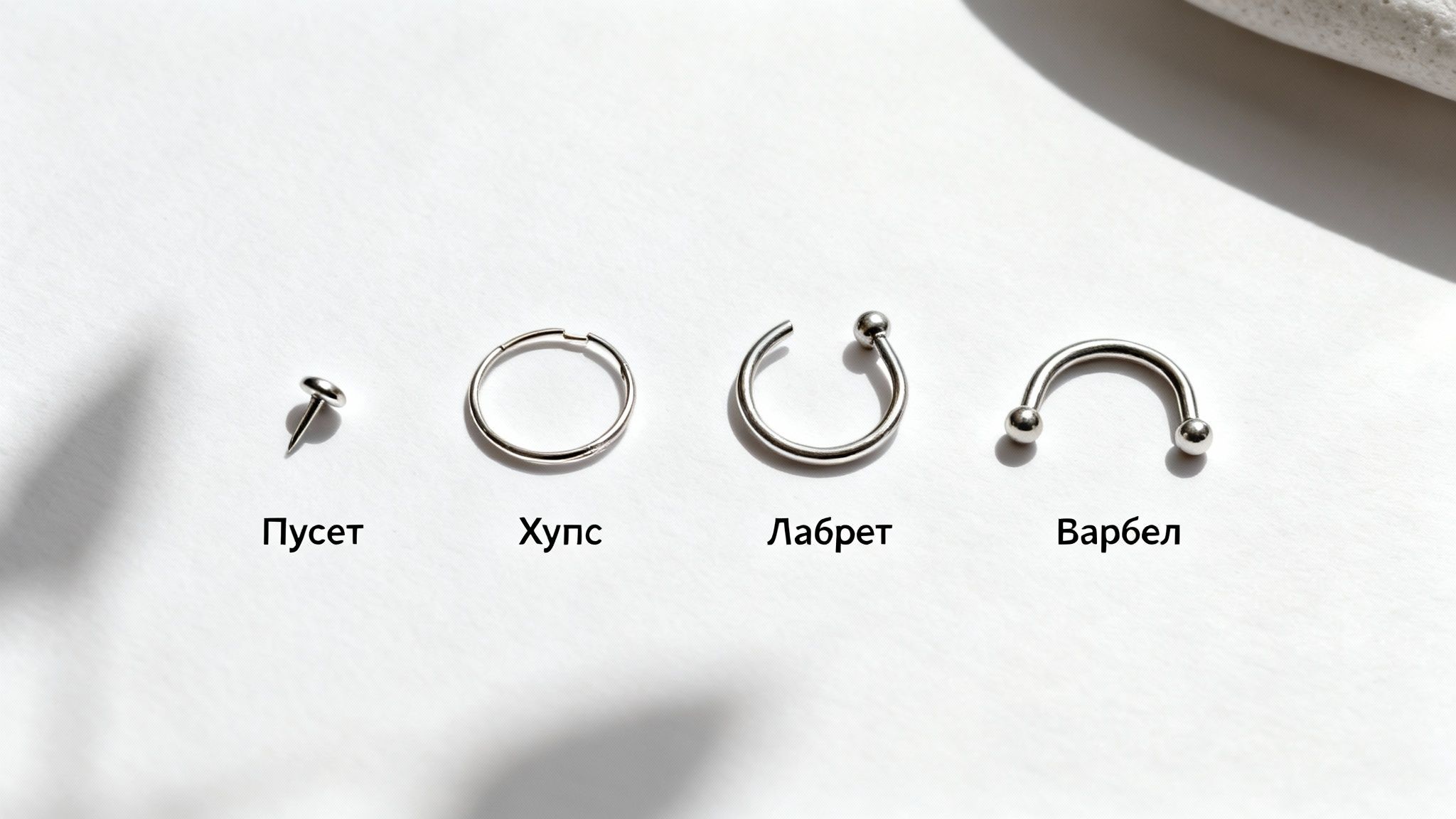 Чотири види металевих прикрас для пірсингу: пусет, хупс, лабрет, варбел, на білому тлі.
