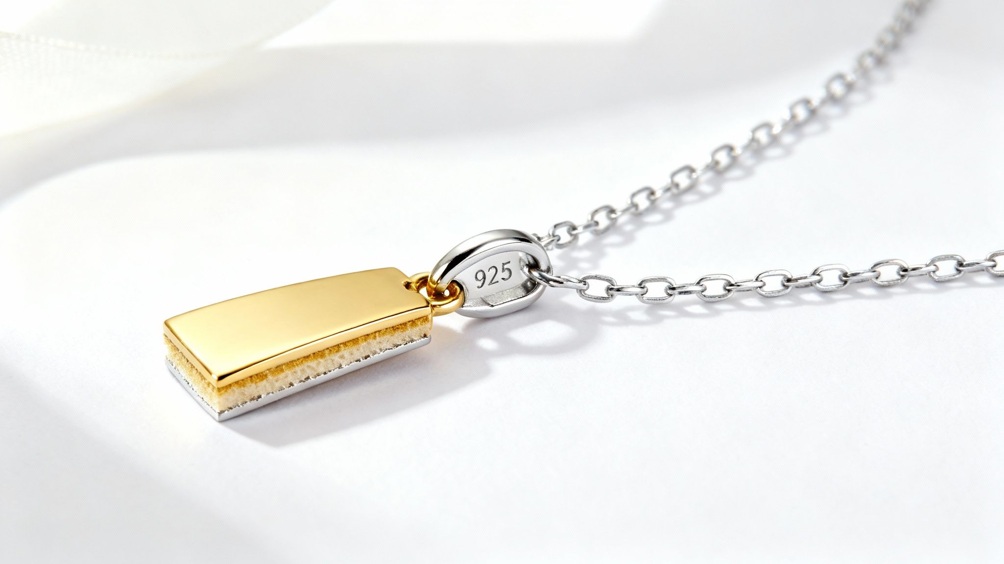 Close-up of a gold vermeil bar pendant with a '925' stamped silver chain on a white background.