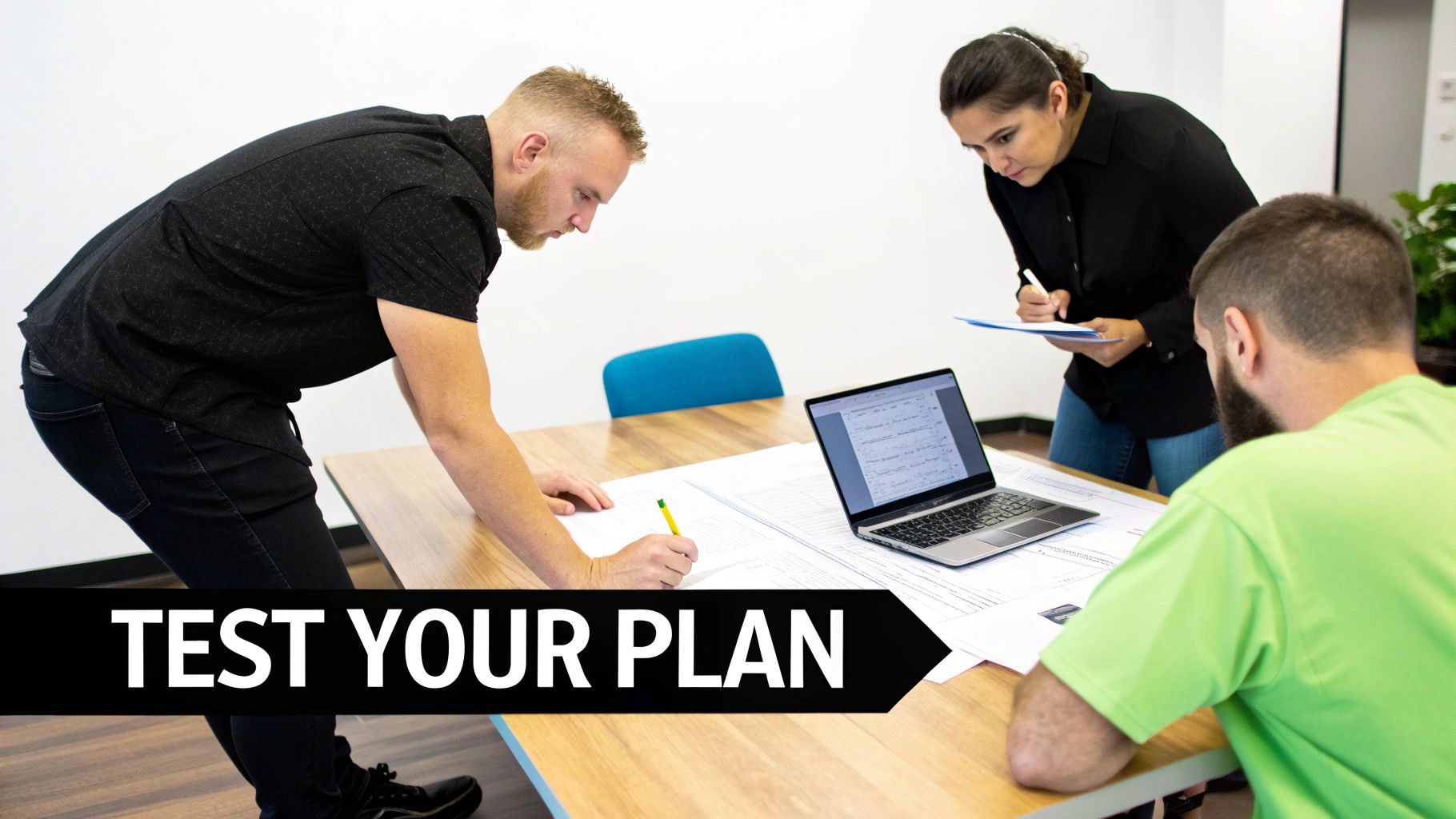 Three professionals collaborate in an office, reviewing documents and a laptop to test their plan.