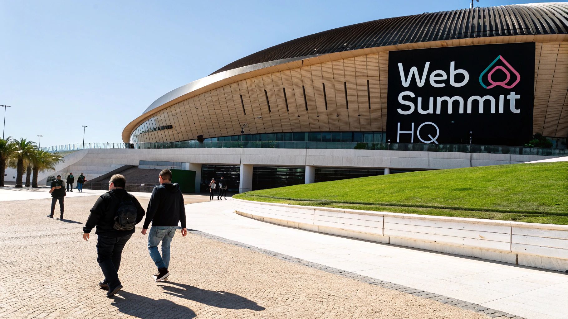 Attendees walk towards the modern Web Summit HQ building on a bright, sunny day.