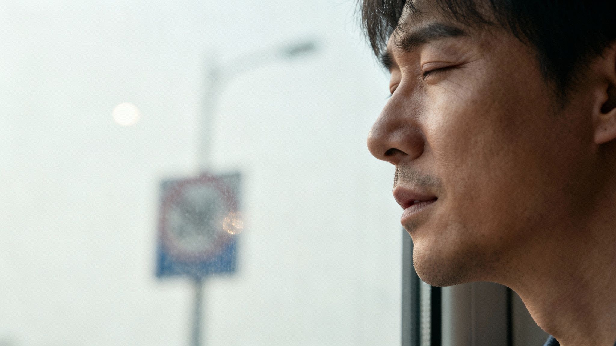 A person holding their head with a blurry, out-of-focus background representing blurry vision.