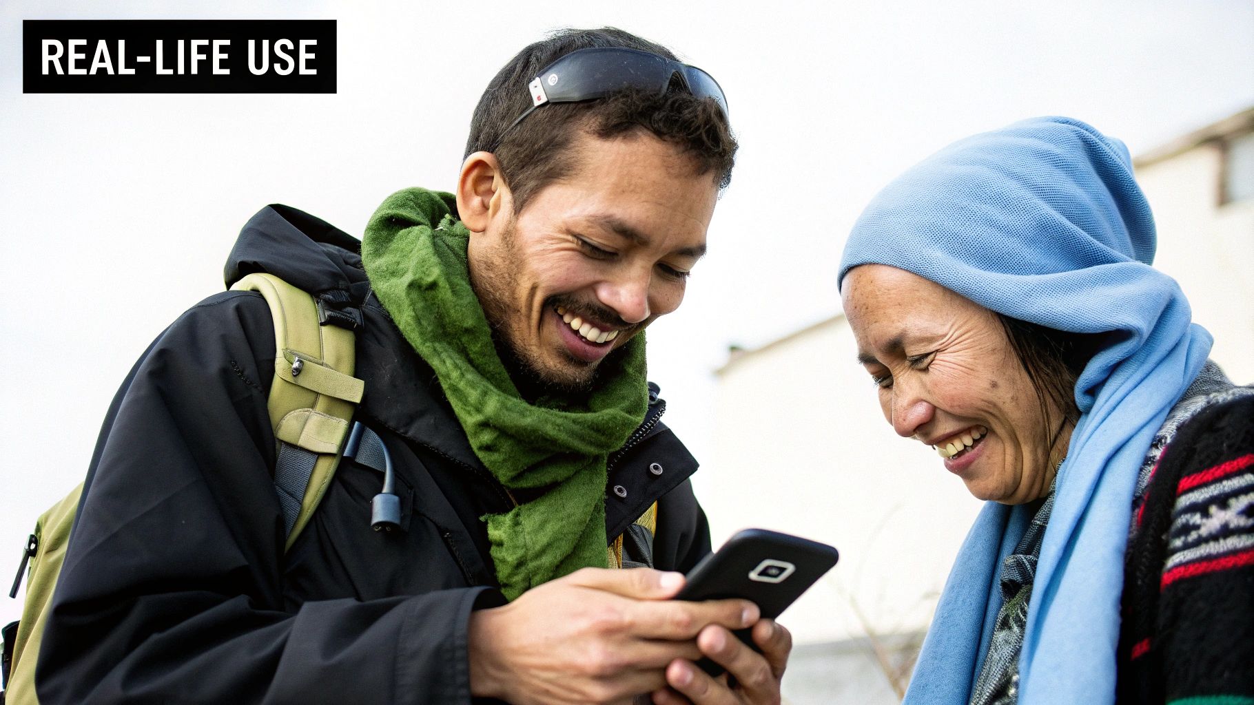 A man and a woman laugh together while looking at a smartphone, demonstrating a real-life use case.