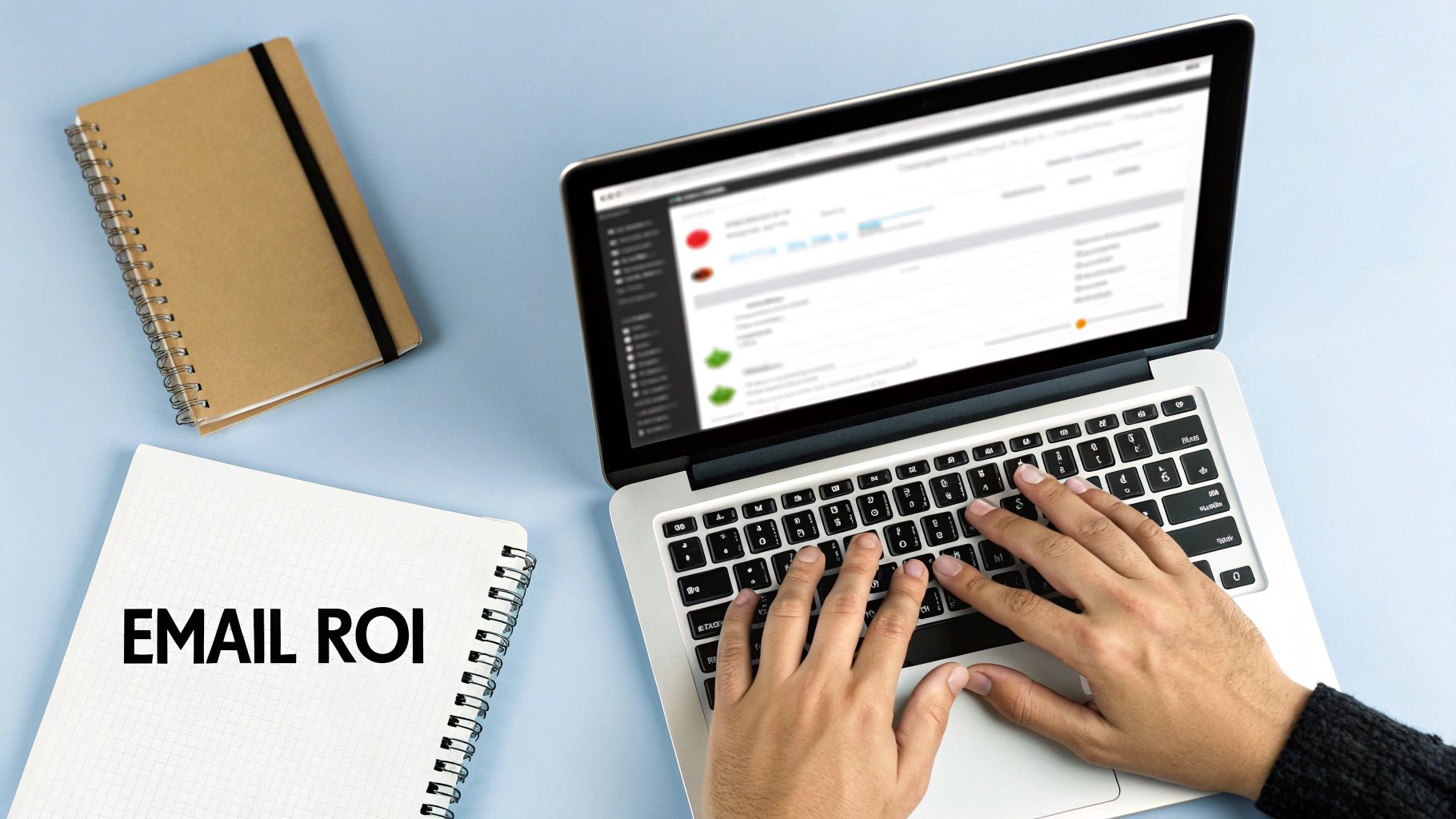 Overhead view of hands typing on a laptop next to two notebooks, one labeled 'EMAIL ROI'.
