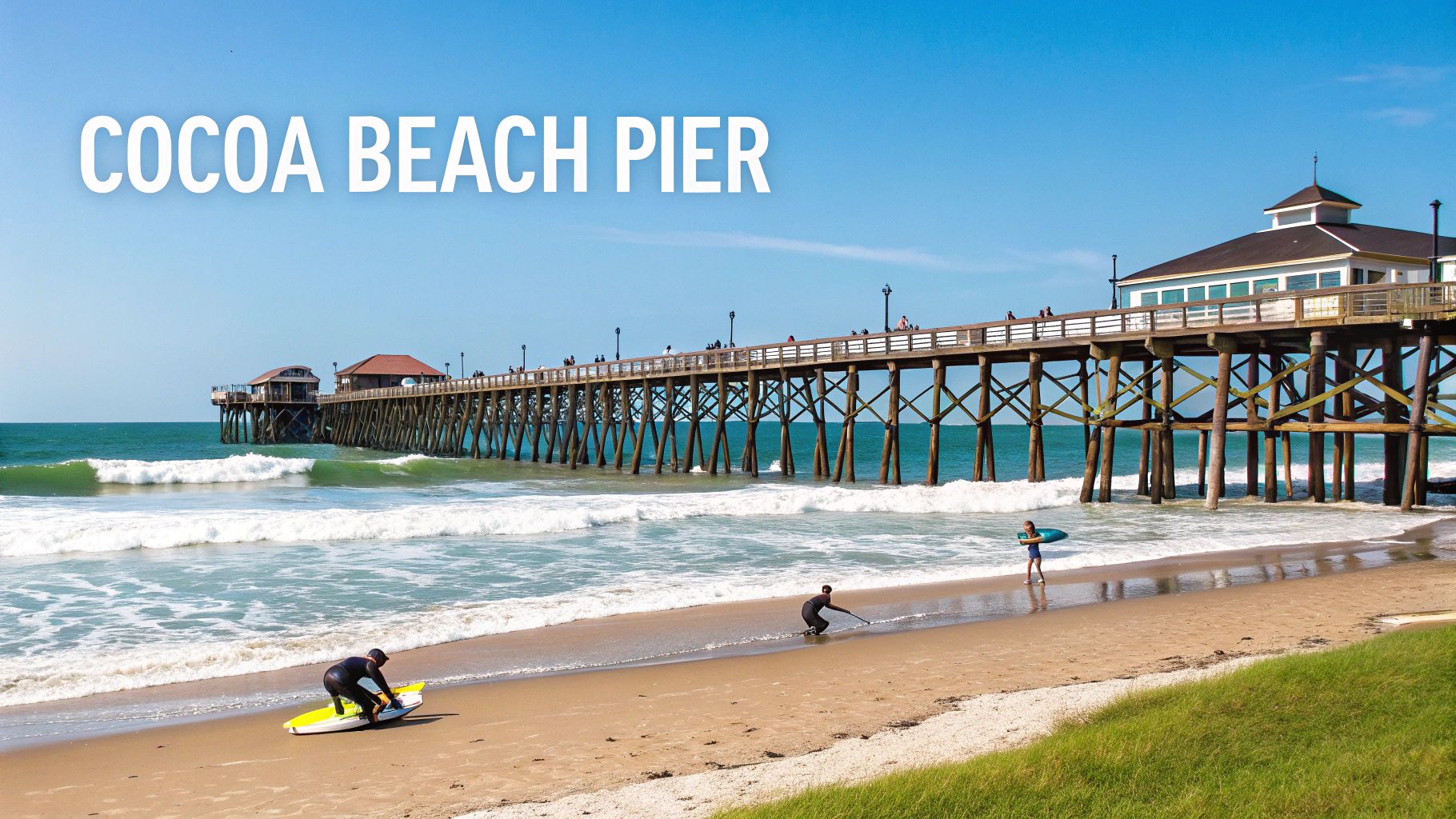A sunny view of Cocoa Beach Pier with people on the sandy beach and in the water.