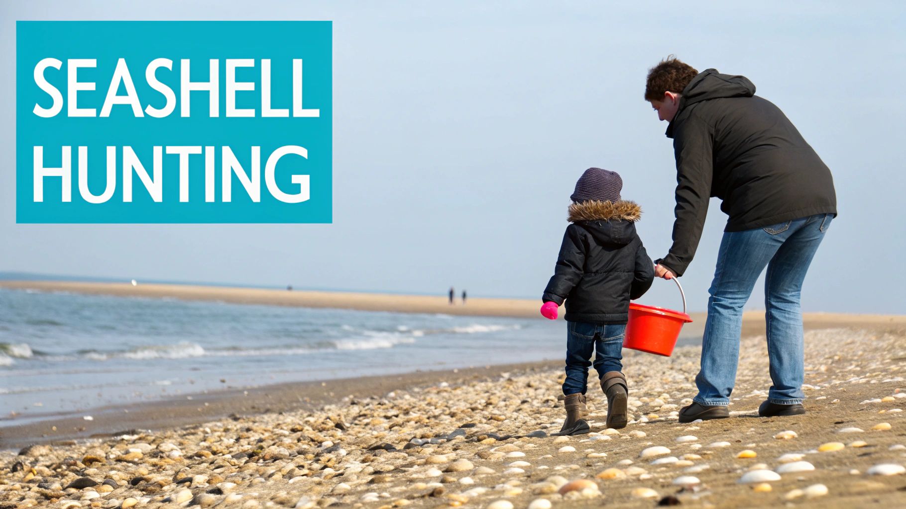 An adult and child seashell hunting on a wide, sunny beach with a red bucket, ocean in background.