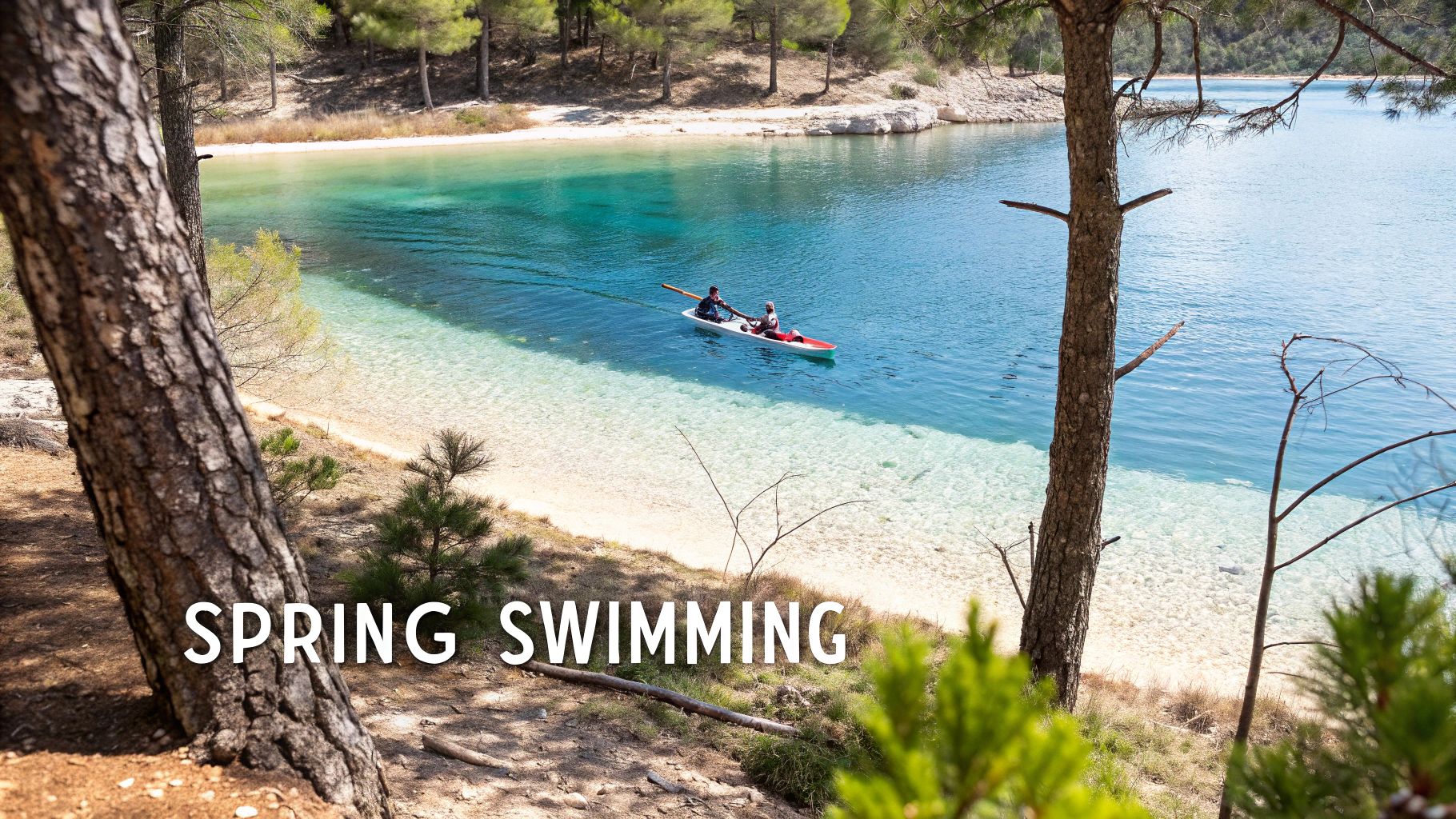 Two people kayak on a serene, clear blue lake with sandy shores, framed by lush trees.