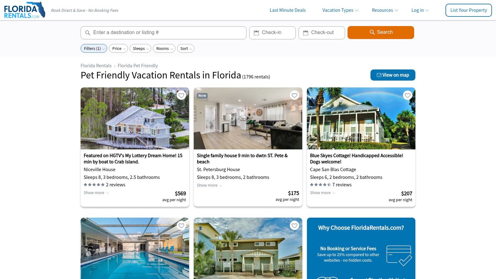 A small dog sitting on the porch of a colorful beach vacation rental home.