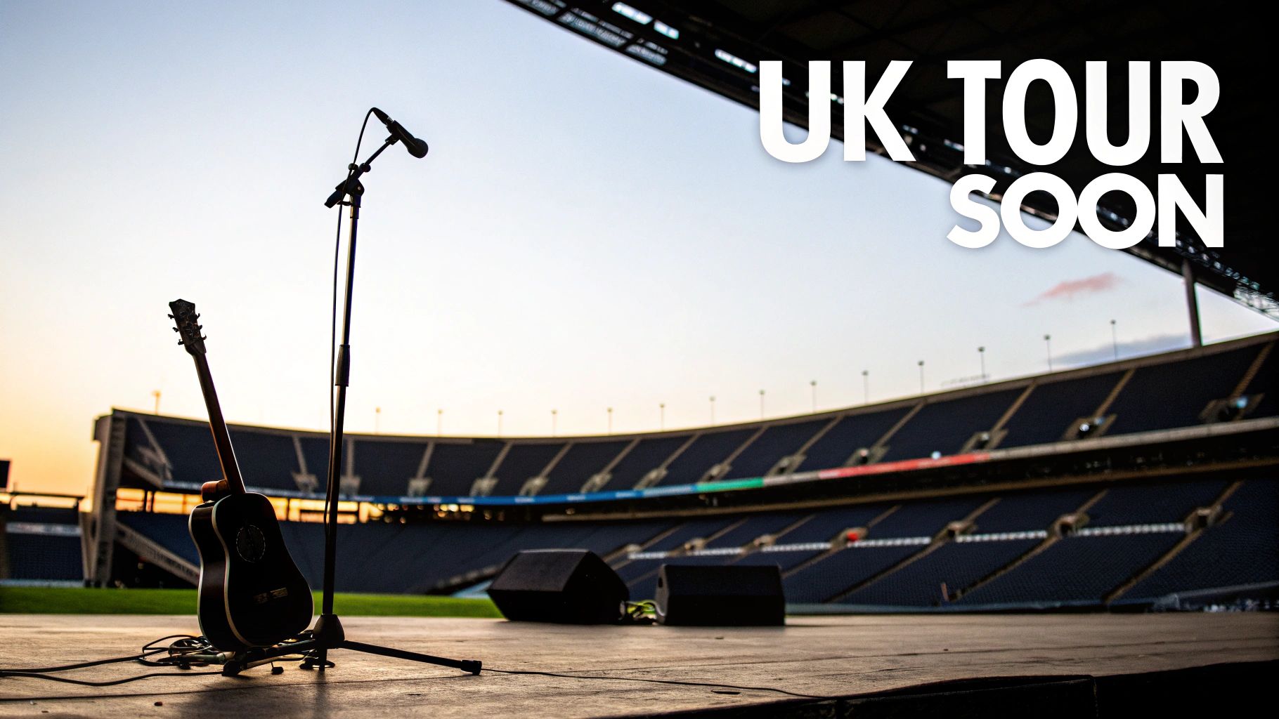 An acoustic guitar and microphone stand on an empty stadium stage at sunset with 'UK TOUR SOON' text.