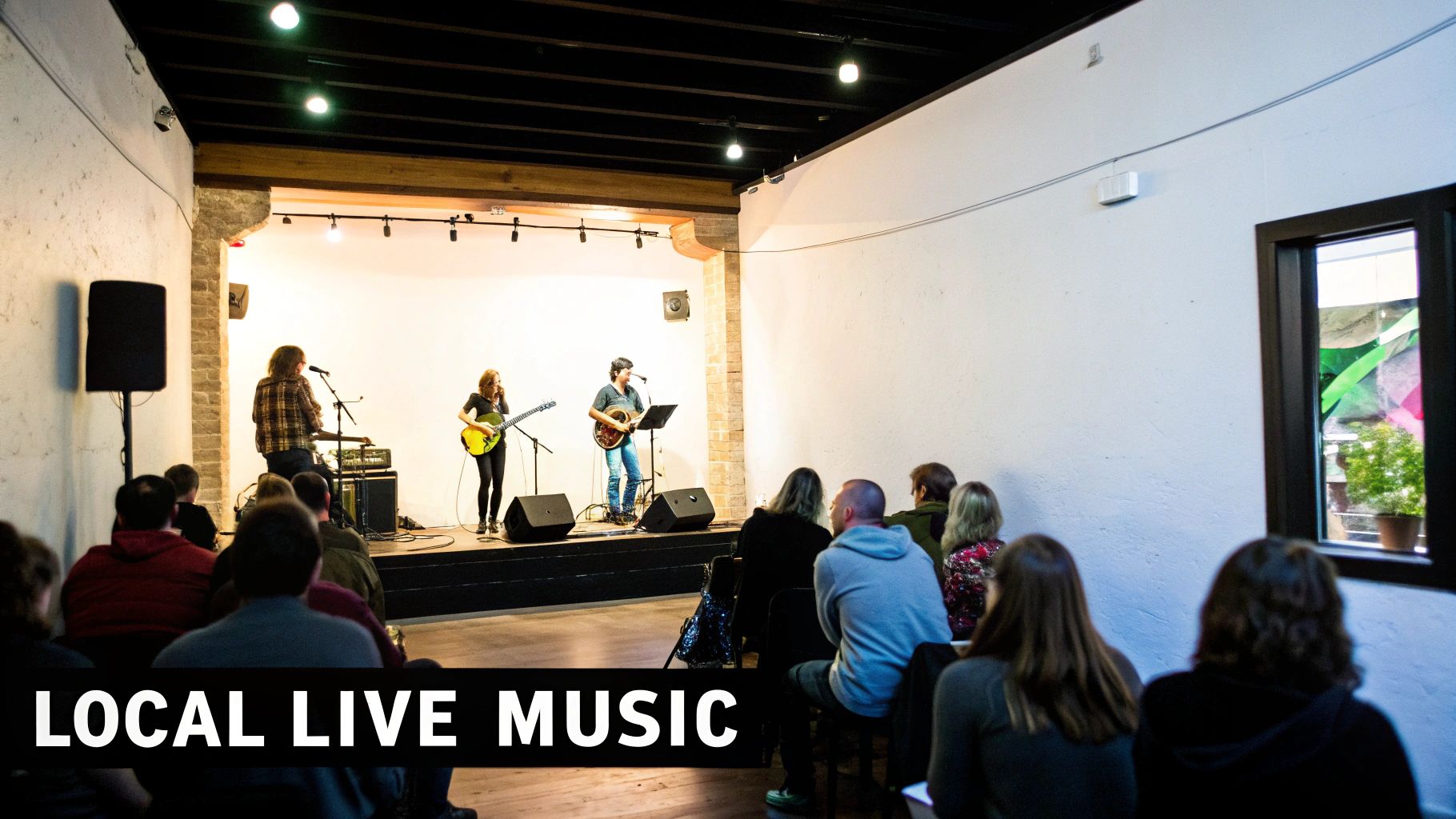 An audience watches three musicians perform live music with guitars and vocals on a stage.