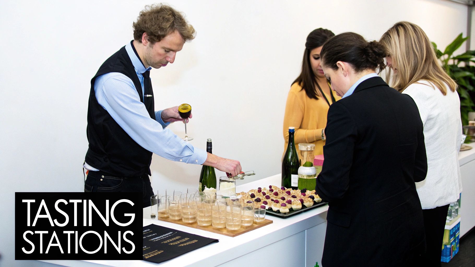 A man pours wine into glasses at a tasting station with desserts and attendees observing.