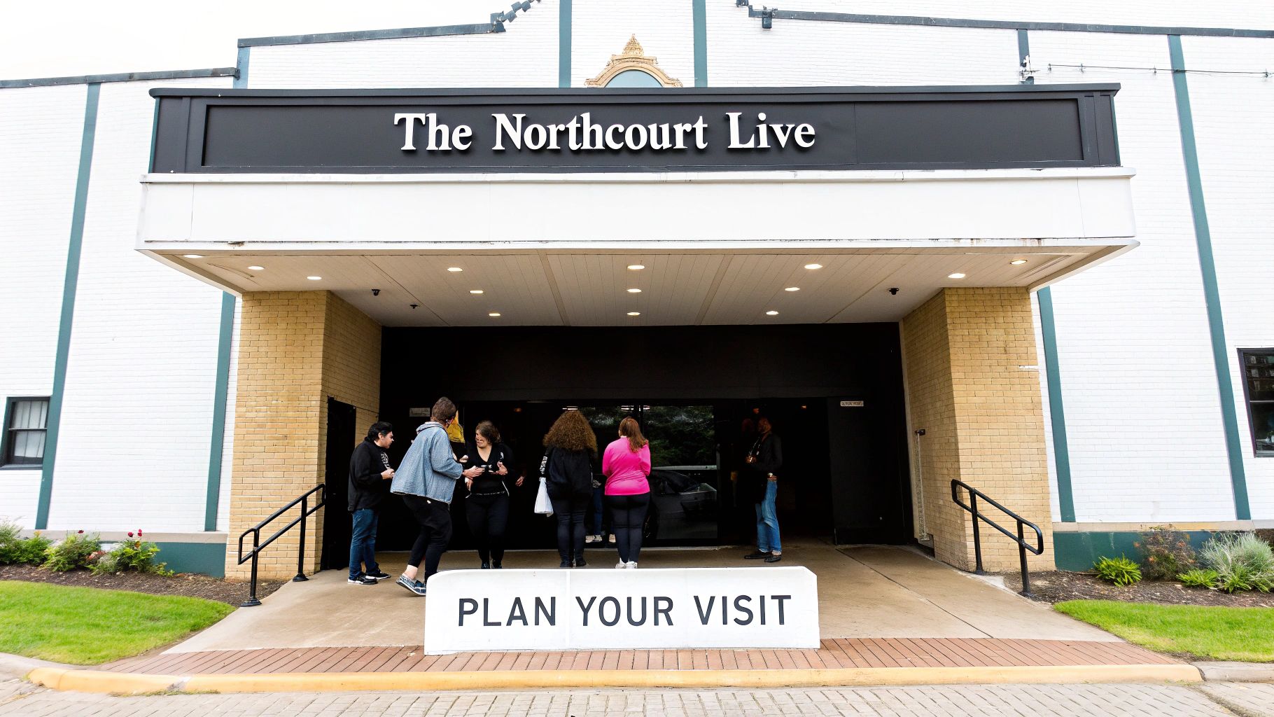 Exterior view of The Northcourt Live venue entrance with several people walking in and a 'Plan Your Visit' sign.