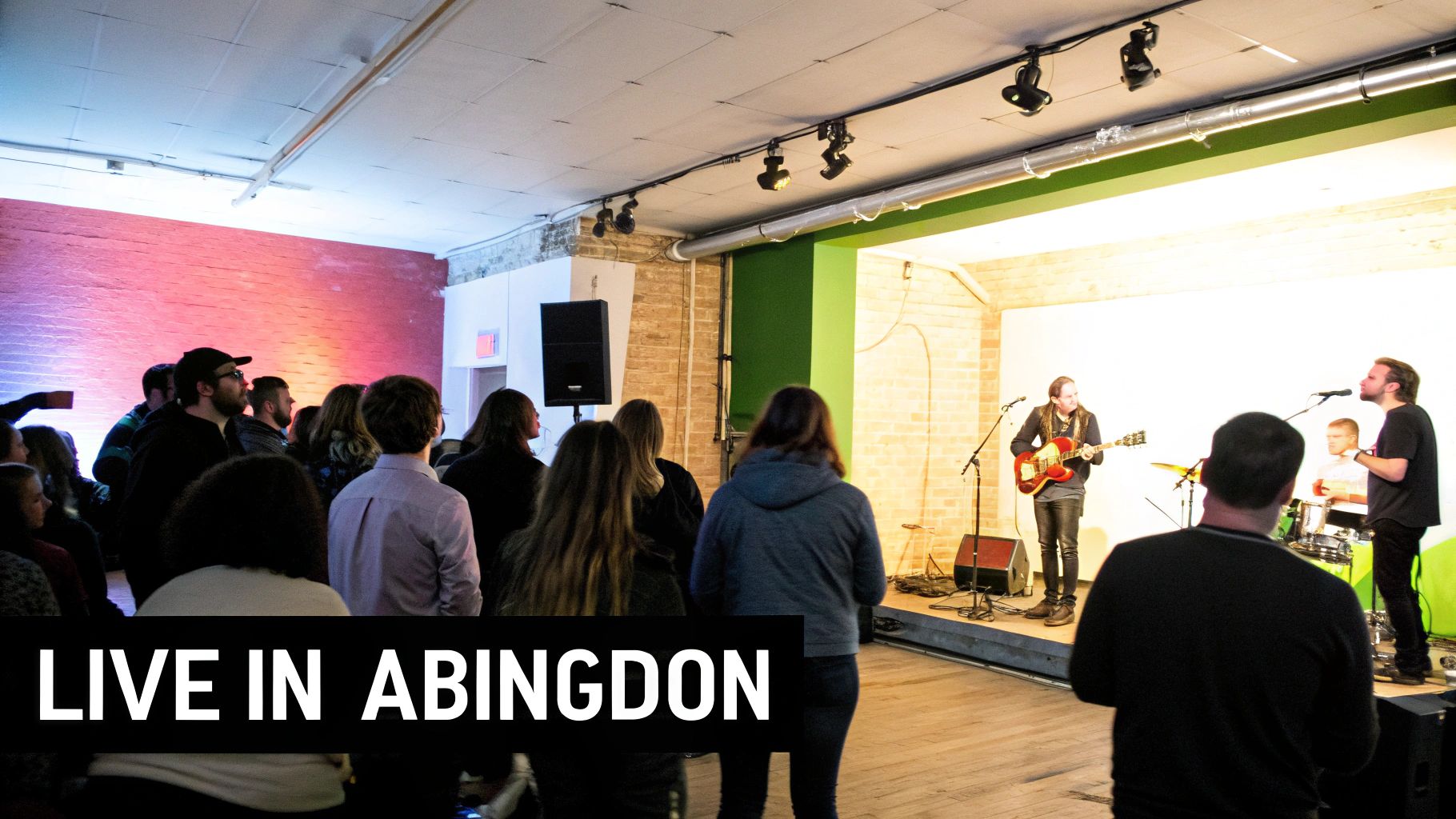 An audience watches a live band perform on stage with a guitarist and singer.