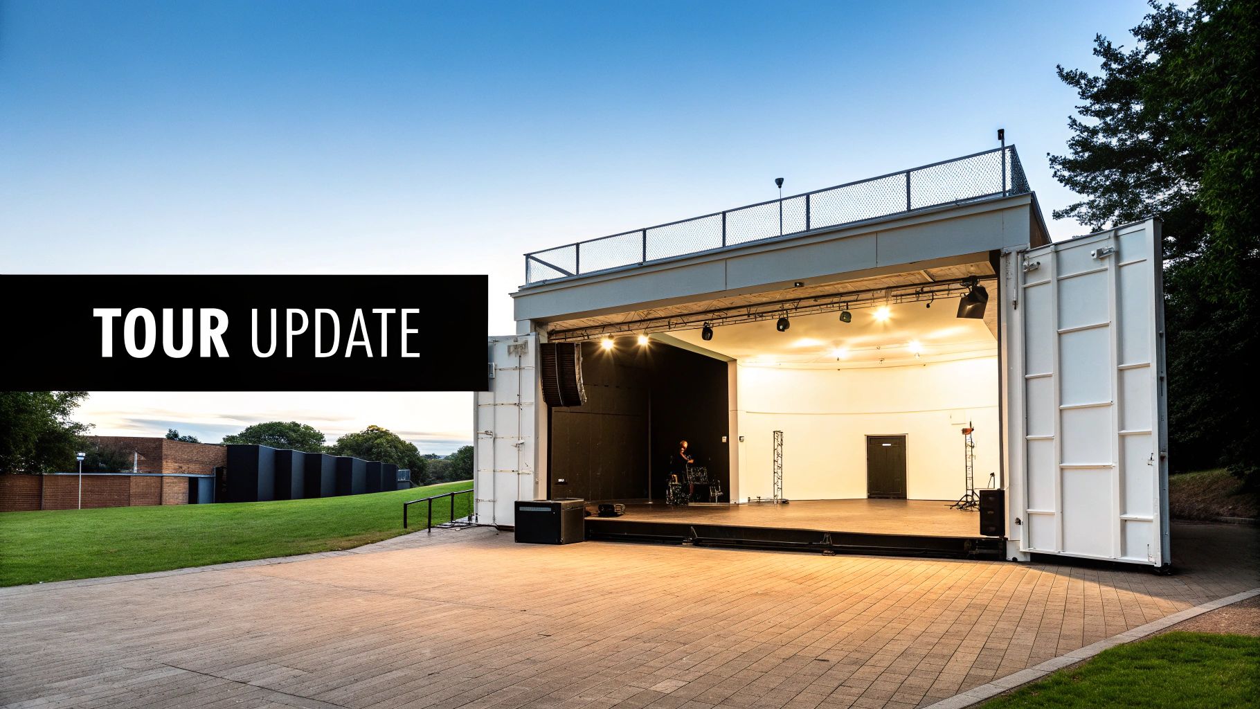 Modern outdoor music stage with a drum kit and spotlights, surrounded by greenery under a clear sky.
